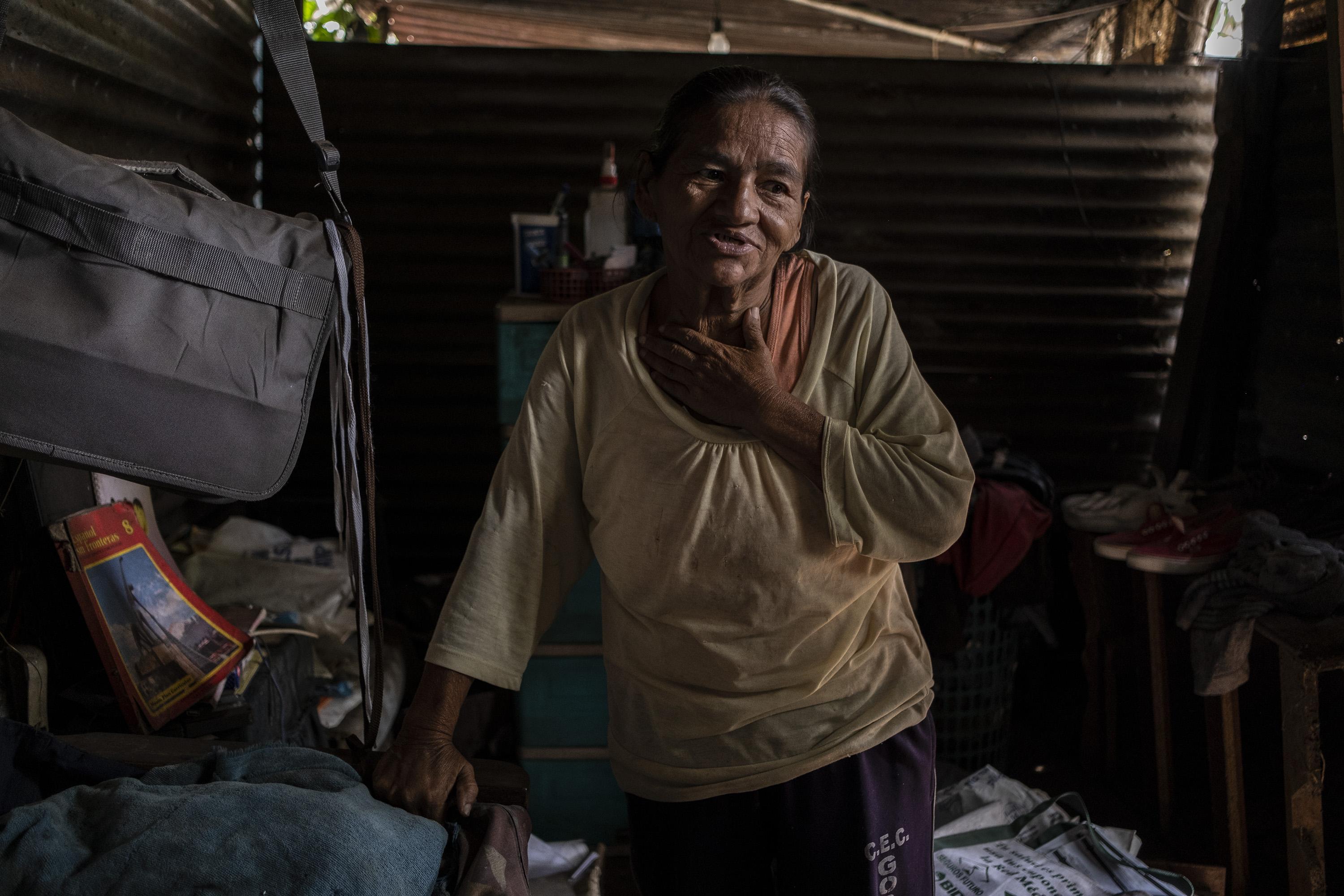 Gloria Marina Flores López, de 64 años, vive en una casa de láminas y madera en la comunidad Gerardo Barrios, cantón Cantarrana, Santa Ana. Gloria es madre de Marvin Alexander Flores, de 29 años de edad, estudiante becado de licenciatura en trabajo social de la Universidad Luterana y graduado de la Escuela de Formación Política de la UCA en 2019. Marvin es el sostén económico del hogar, lograban subsistir gracias a la beca universitaria y a su trabajo como fotógrafo de eventos. El 24 de abril, Marvin fue detenido en la colonia La Esmeralda de Santa Ana mientras visitaba a su novia. Fue esposado y, junto a su cuñado, llevado a la Delegación policial de Santa Ana para luego ser enviado al penal de Mariona. Debido a eso, Gloria se quedó sola. Está lesionada de una de sus rodillas, lo que le impide movilizarse con libertad y depende únicamente de la ayuda que sus vecinos puedan darle. Foto de El Faro: Carlos Barrera.