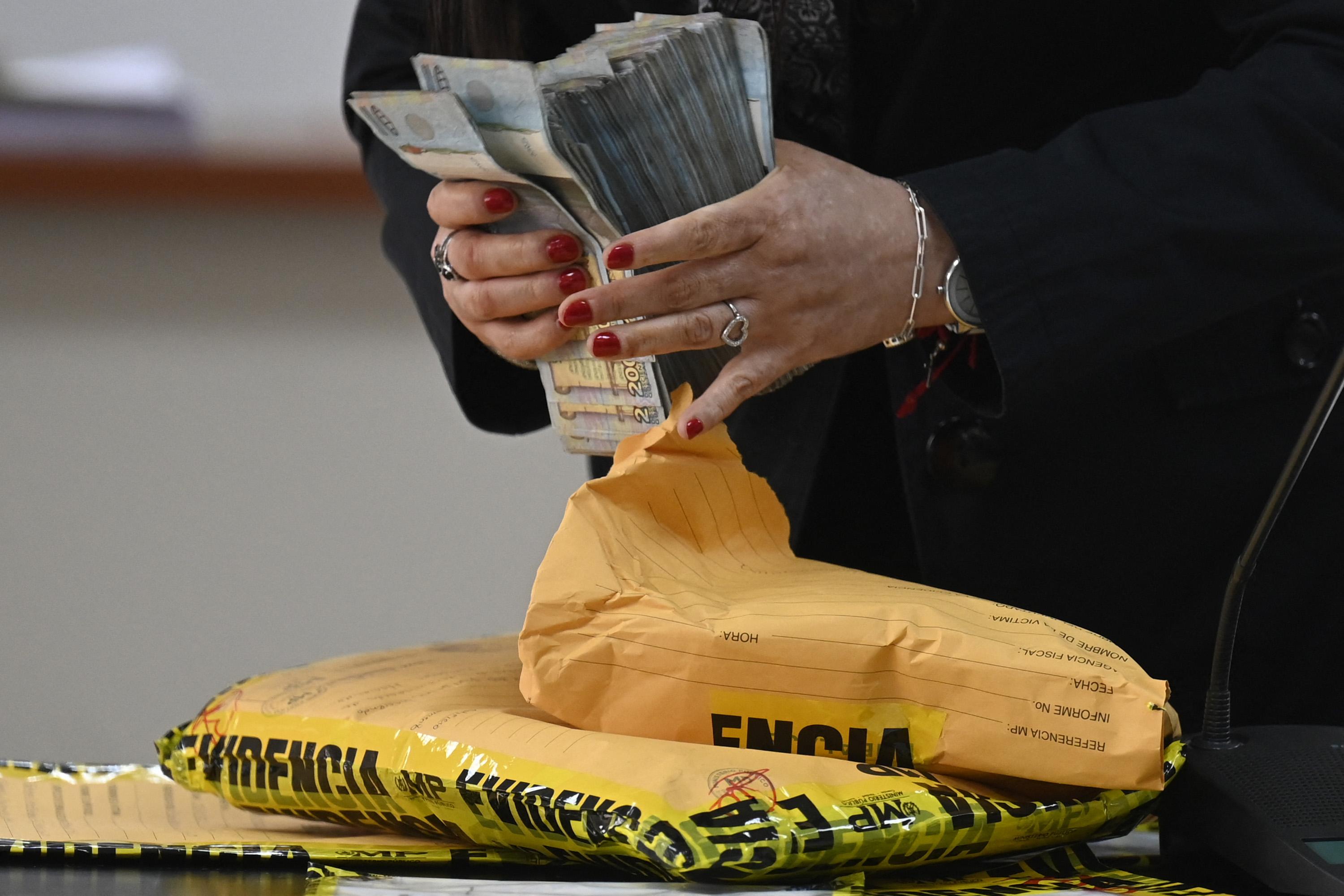 FECI prosecutor Cynthia Monterroso handles money presented as evidence in the trial against Guatemalan journalist José Rubén Zamora. Photo: Johan Ordóñez/AFP