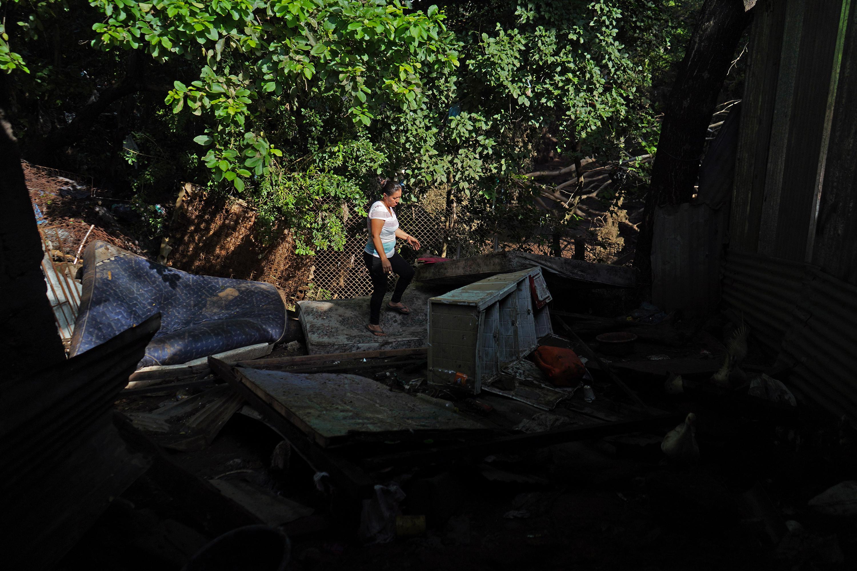 María Florinda García recupera algunas pertenencias que se quedaron atrapadas en una cerca de la vivienda, en la comunidad El Tiangue, de San Miguel. Esto era la habitación de su hija, que fue arrastrada por las aguas del río Grande, que se desbordó a las 1:00 de la mañana del lunes 10 de octubre, pero que también inundó las seis casas cercanas a la ribera a las 4:00 de la madrugada. En esta casa viven cinco hombres que trabajan como ayudantes de albañilería; tres mujeres y un niño de nueve meses. Todos ahora comparten un mismo cuarto mientras reconstruyen.