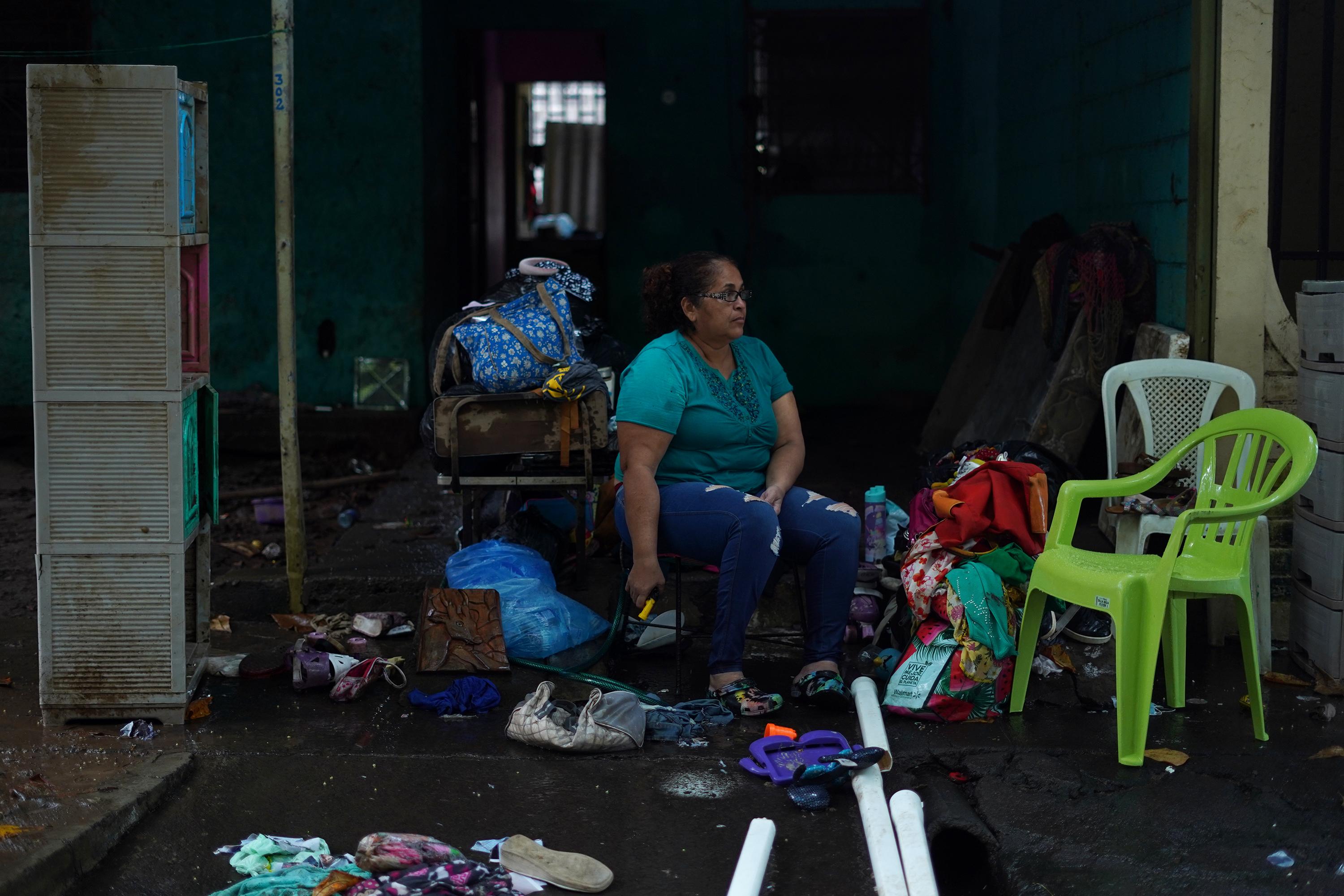 Nahil Guadalupe Hernández, de 53 años, lava los zapatos, sandalias, patines y algunas prendas que quedaron de su pequeño negocio, una venta de ropa americana de segunda mano. Perdió todo: Sillones, cama, cocina, refrigeradora y alrededor de $500 de inversión del negocio con el que sobreviven ella y sus dos hijos. Ella vive en la colonia Jardines del Río, en San Miguel. Aquí el agua avanzó casi 100 metros y cubrió con más de dos metros más de 40 casas de los primeros tres pasajes. Nahil tiene una fractura en su pie izquierdo que le dificulta la movilidad, pero regresa a la casa durante el día para limpiar y recuperar más cosas. Por las noches vuelve a casa de su hermana, donde se refugia desde el 10 de octubre. En 1998, el Huracán Mitch también inundó su casa y destruyó todas sus pertenencias.  