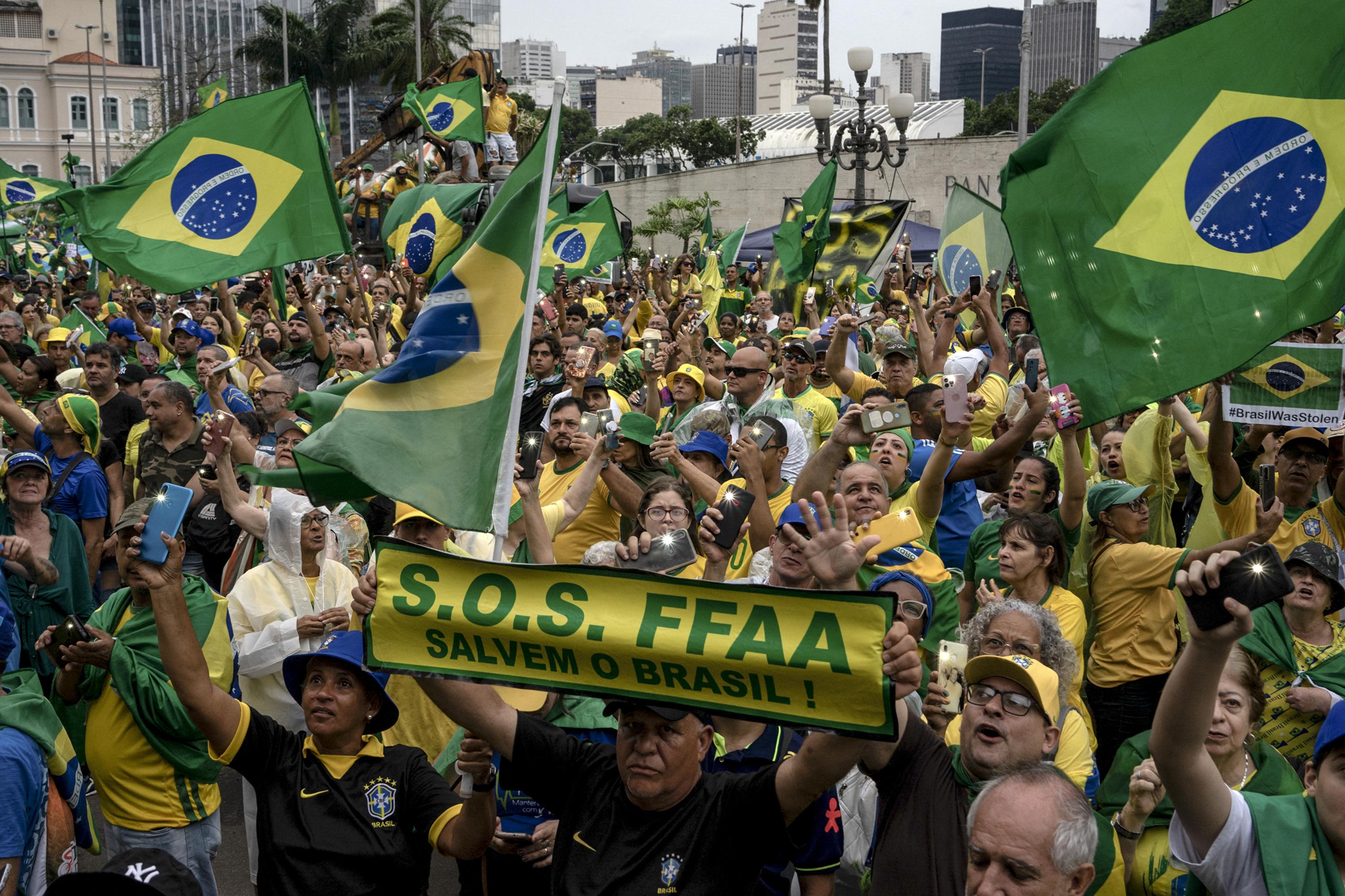 Los partidarios del presidente brasileño Jair Bolsonaro sostienen carteles que piden la intervención militar durante una manifestación contra los resultados de la segunda vuelta electoral, frente a la sede del Comando Militar Oriental (CML), en el centro de Río de Janeiro, Brasil, el 15 de noviembre de 2022. - Miles de brasileños se reunieron frente a los cuarteles del Ejército en Río de Janeiro, Brasilia y otras ciudades exigiendo la intervención militar para evitar que el presidente electo de izquierda, Luiz Inácio Lula da Silva, asuma el poder el próximo año. (Foto por TERCIO TEIXEIRA / AFP)