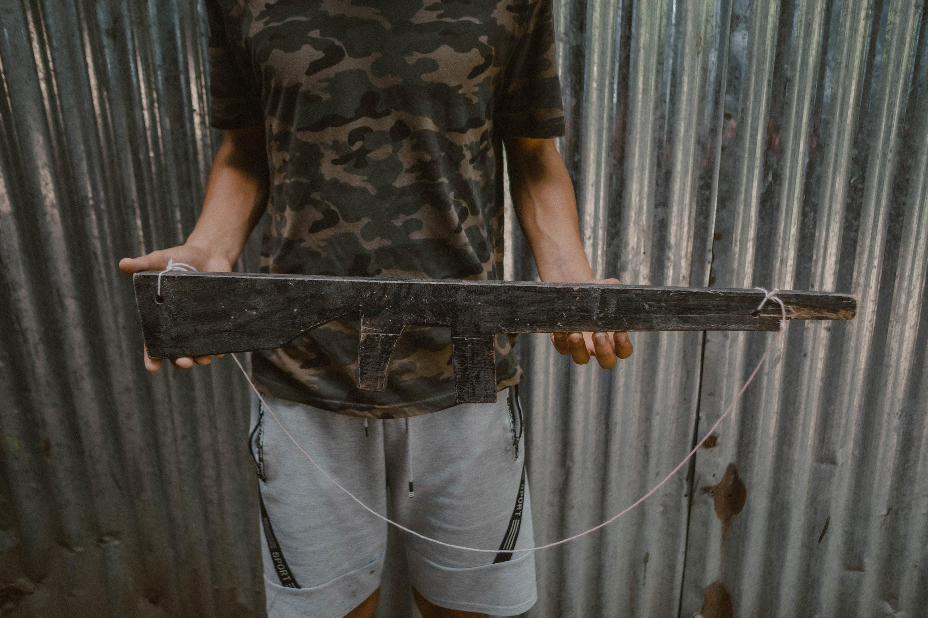 Daniel, de 16 años, sostiene un fusil de madera que él y algunos de sus compañeros utilizaron durante una obra de teatro que presentaron el 30 de octubre, como parte de la celebración local del 