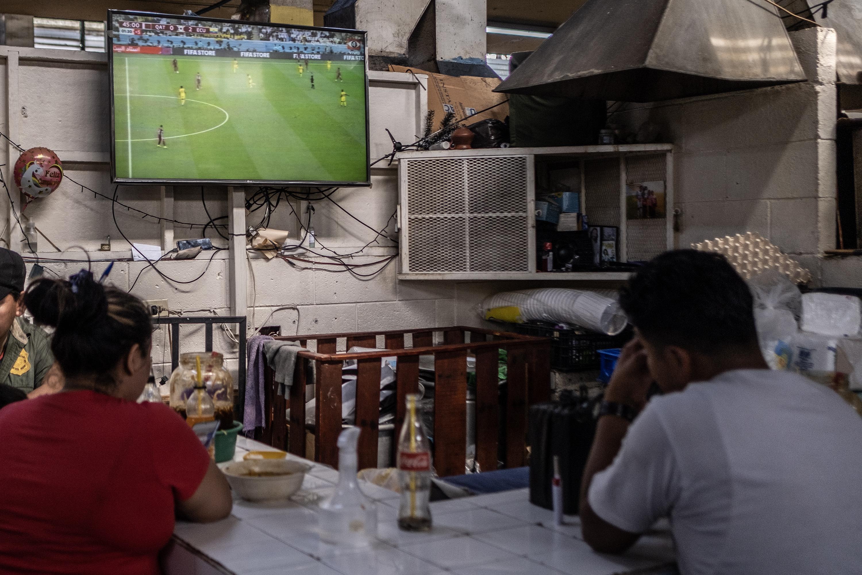 Algunos clientes de un comedor del mercado Central, San Salvador, llegaron temprano para poder ver el partido de inauguración de la Copada del Mundo Qatar 2022. El encuentro lo disputaría la selección qatarí contra Ecuador. Foto de El Faro: Carlos Barrera