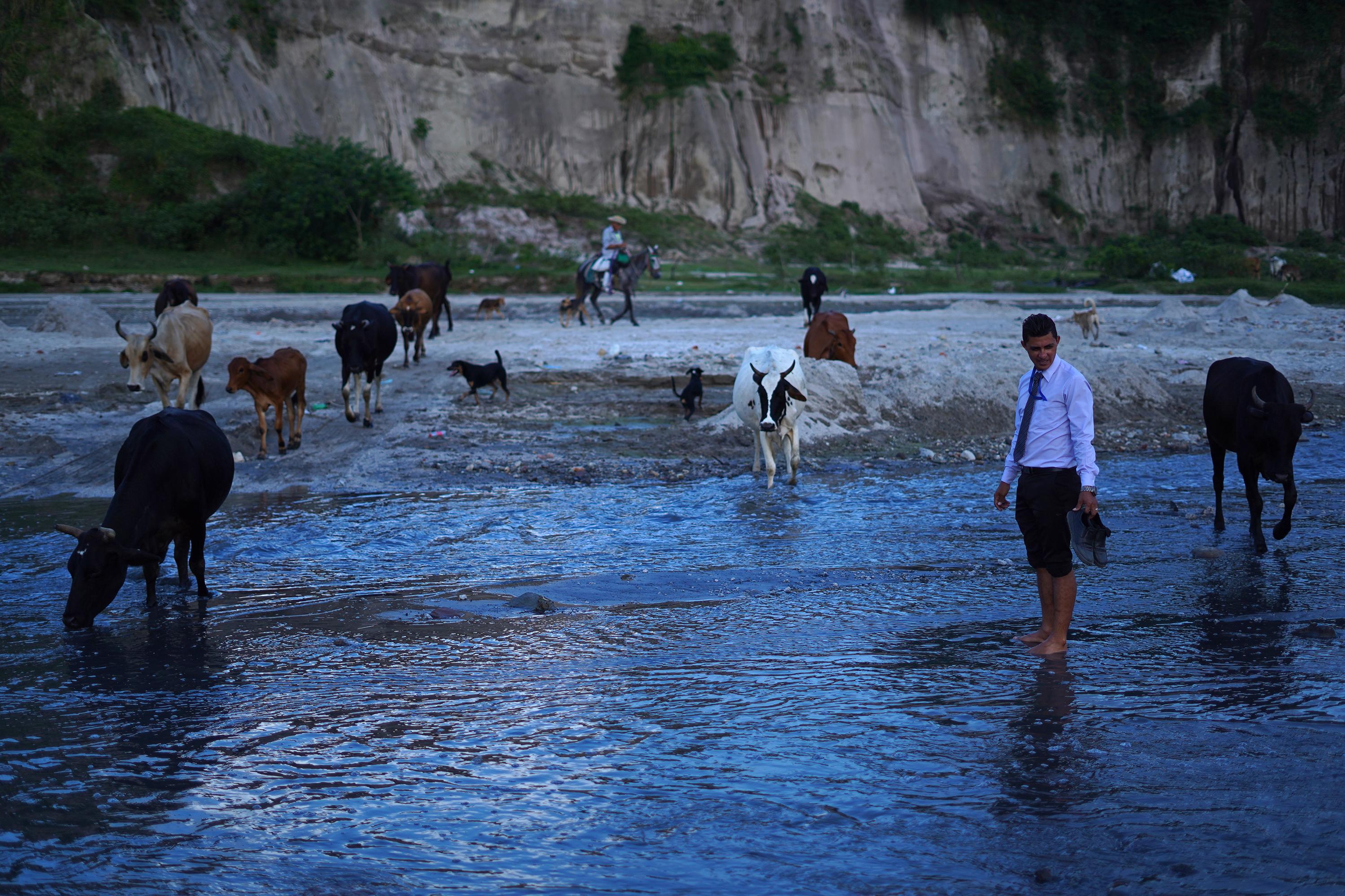 Miguel Ángel Sales cruza el río Las Cañas, un cauce de cinco metros de ancho donde corren las aguas negras que provienen del oriente de San Salvador. Aquí es el límite de los municipios de Soyapango y Tonacatepeque, del departamento de San Salvador, y donde en septiembre de 2022 este profesor de secundaria encontró un nuevo sitio arqueológico ubicado en medio de dos comunidades violentas que han estado bajo el control de las pandillas. Foto de El Faro: Víctor Peña.