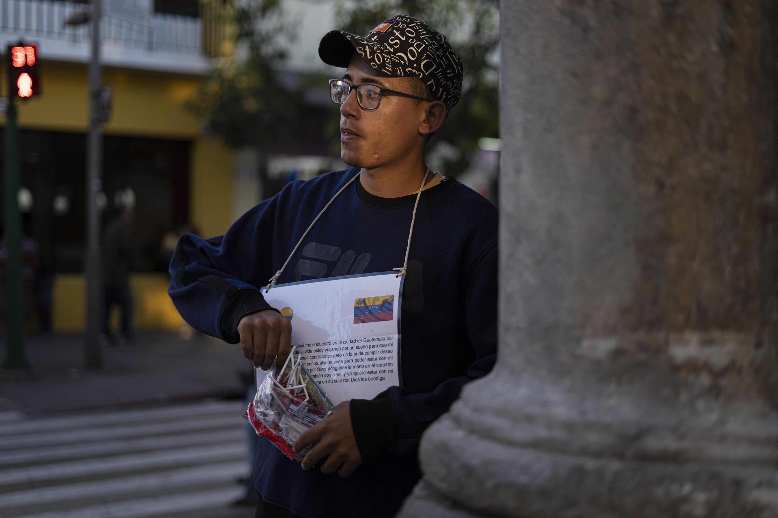 Juan vende dulces sobre la Sexta avenida, frente a la conocida panadería San Martín. Es su esquina fija todos los días. Ahí consigue algo para comer con su bolsa de dulces en mano y un cartel que lo identifica como otro venezolano varado en Ciudad de Guatemala. Foto de El Faro: Víctor Peña.