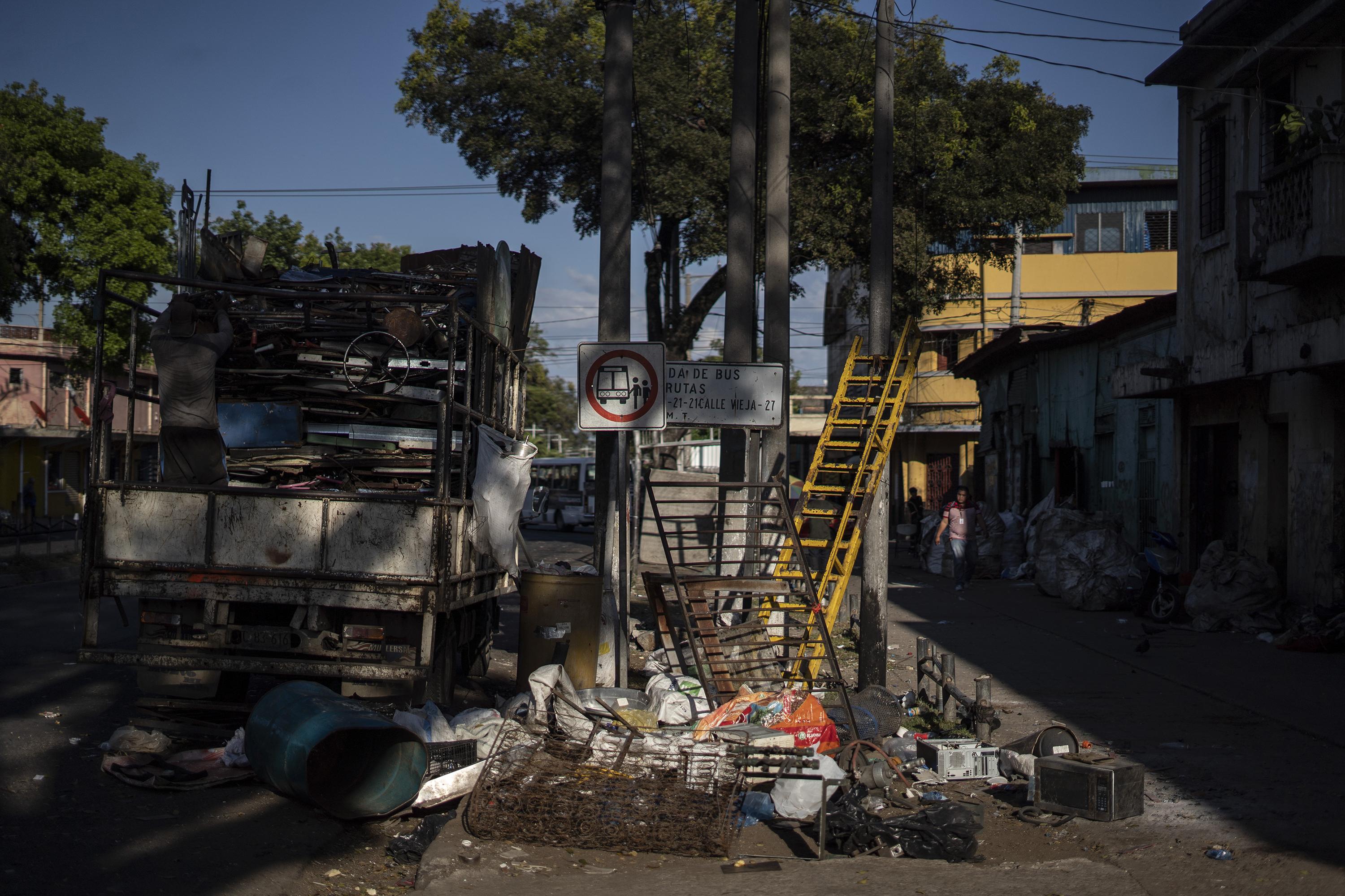 Chatarra acumulada sobre la avenida Independencia, en el Centro de San Salvador. Este punto también era una de las fronteras invisibles que las pandillas establecieron y donde mantenían control permanente. Foto de El Faro: Víctor Peña. El árbol del medio de la imagen dividía la zona de control de la MS-13 con la del Barrio 18 Revolucionarios, y la cuadra era zona de constantes valaceras. 