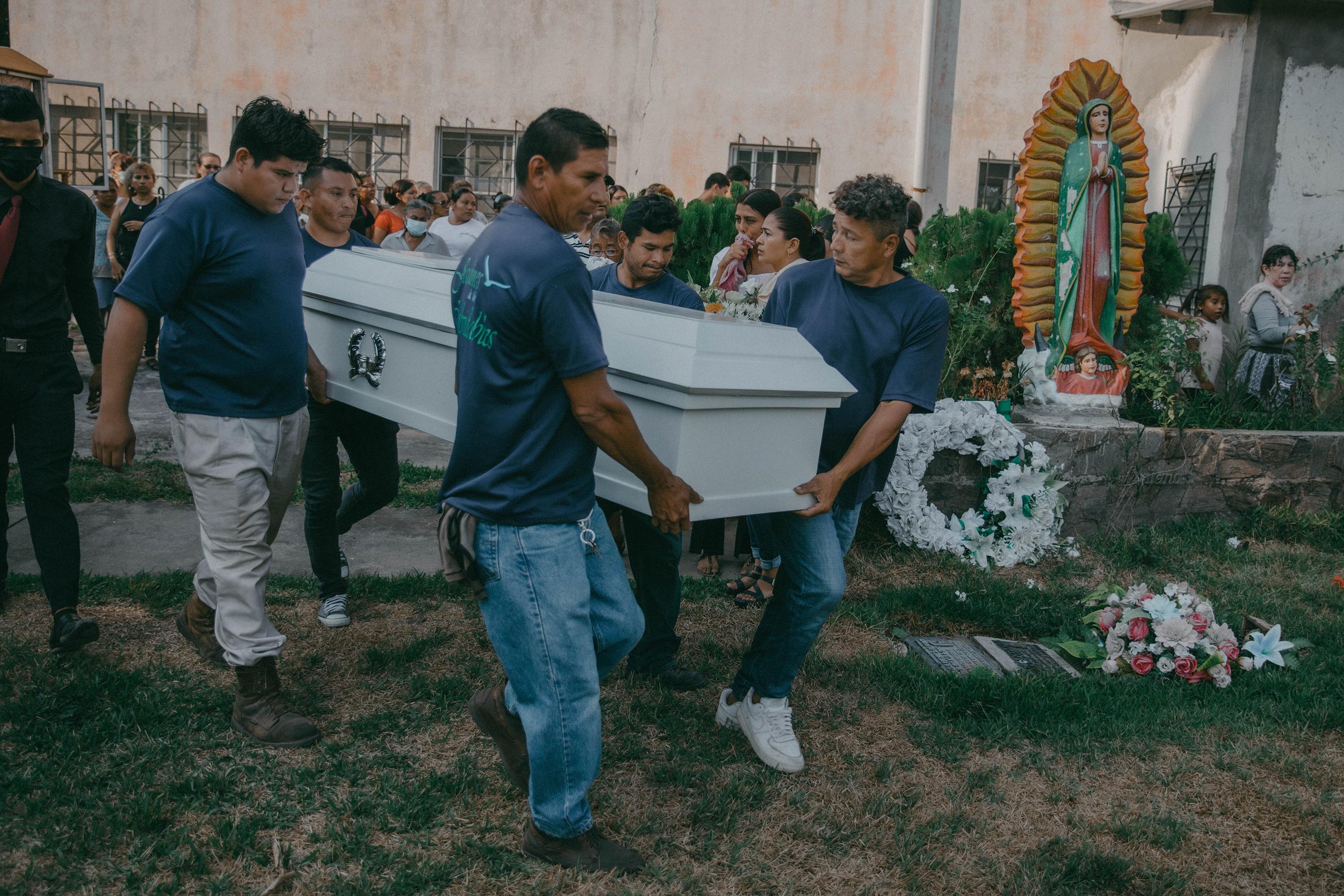 Empleados de una funeraria cargan el ataúd con los restos de Rodrigo Vásquez, de 44 años, que fue detenido el 9 de mayo de 2022 bajo el régimen de excepción de El Salvador y murió en la cárcel de Izalco. Según medicina legal, Vásquez murió por una neumonía. Foto de El Faro: Carlos Barrera.