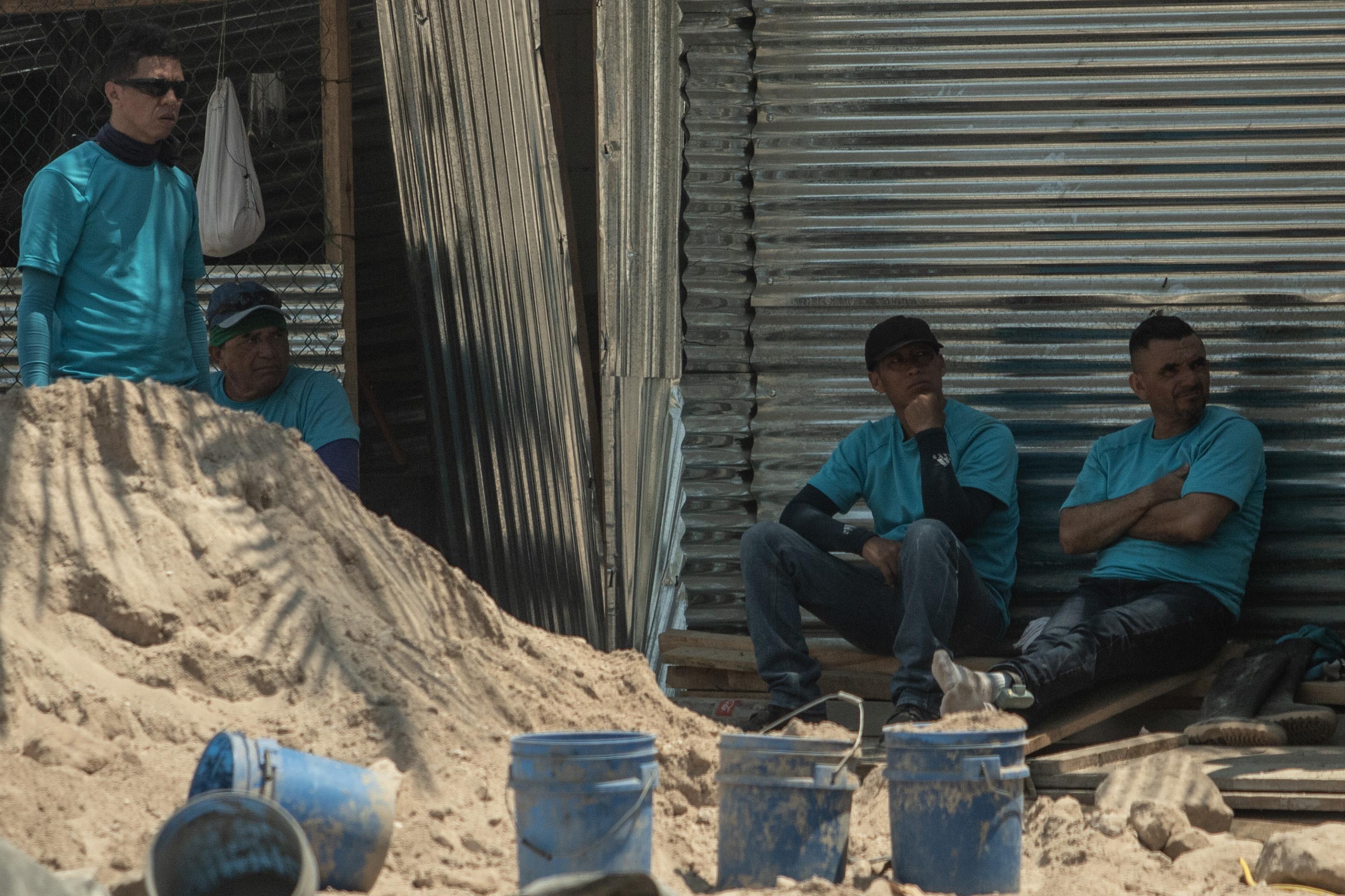 Durante unos minutos de la tarde del 11 de abril de 2023, los reos del Centro de Detención Menor de Zacatecoluca se protegieron del sol en la construcción que realizan en una propiedad privada en la playa Las Hojas. En la pierna izquierda del primero a la derecha se observa uno de los grilletes utilizados por los detenidos en fase de confianza. Foto de El Faro: Carlos Barrera.