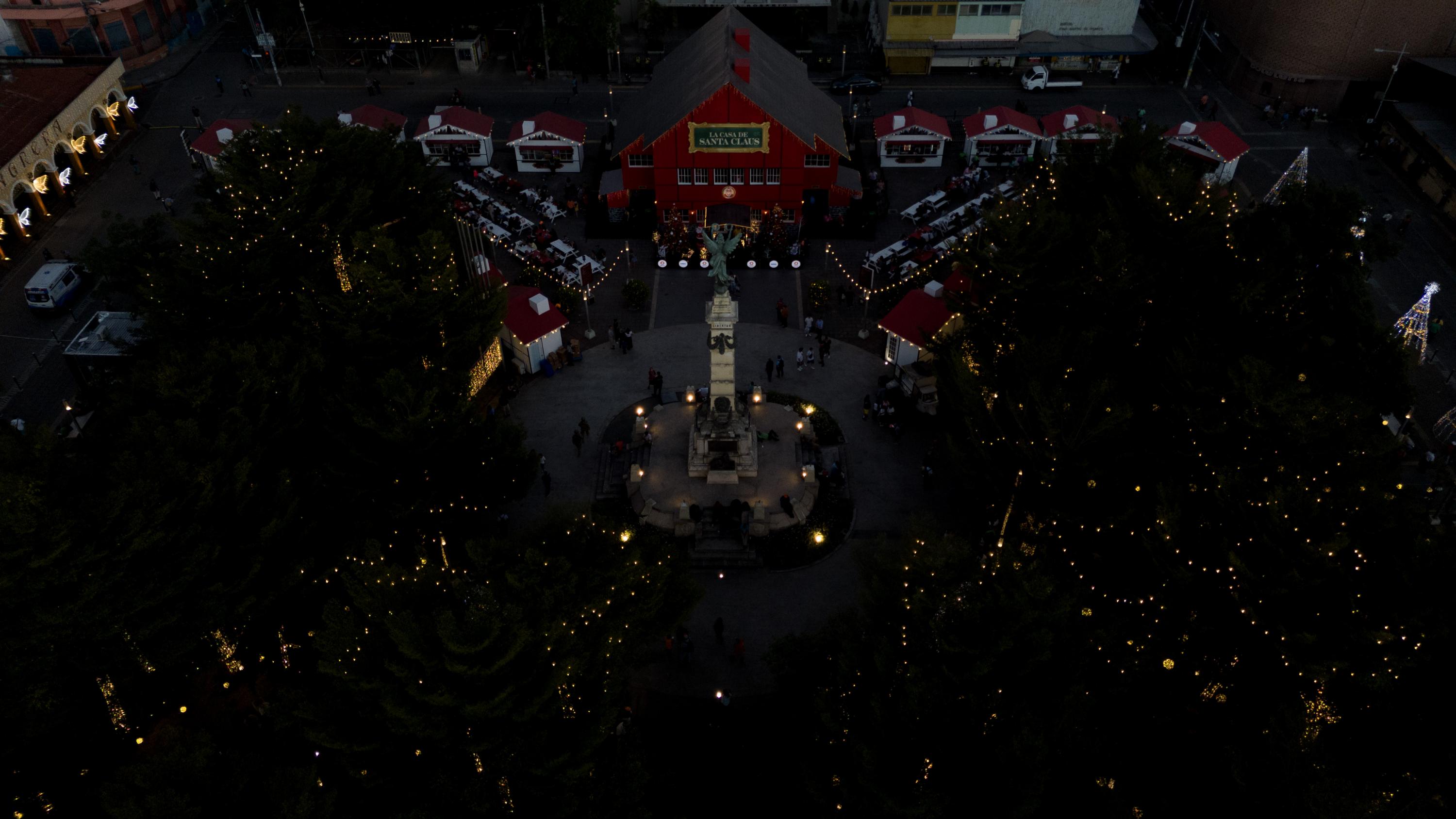 The monument in Plaza Libertad is surrounded by a villa with a house standing in the center. In front of the big red house the sign “La Casa de Santa Claus” (Santa’s House) welcomes visitors. At the base of the house, digital signs advertise bitcoin. Dozens of people attracted by the lights and food crowd the square. This public space is off-limits to street vendors who make a living offering products in the Historic Center. Photo Carlos Barrera