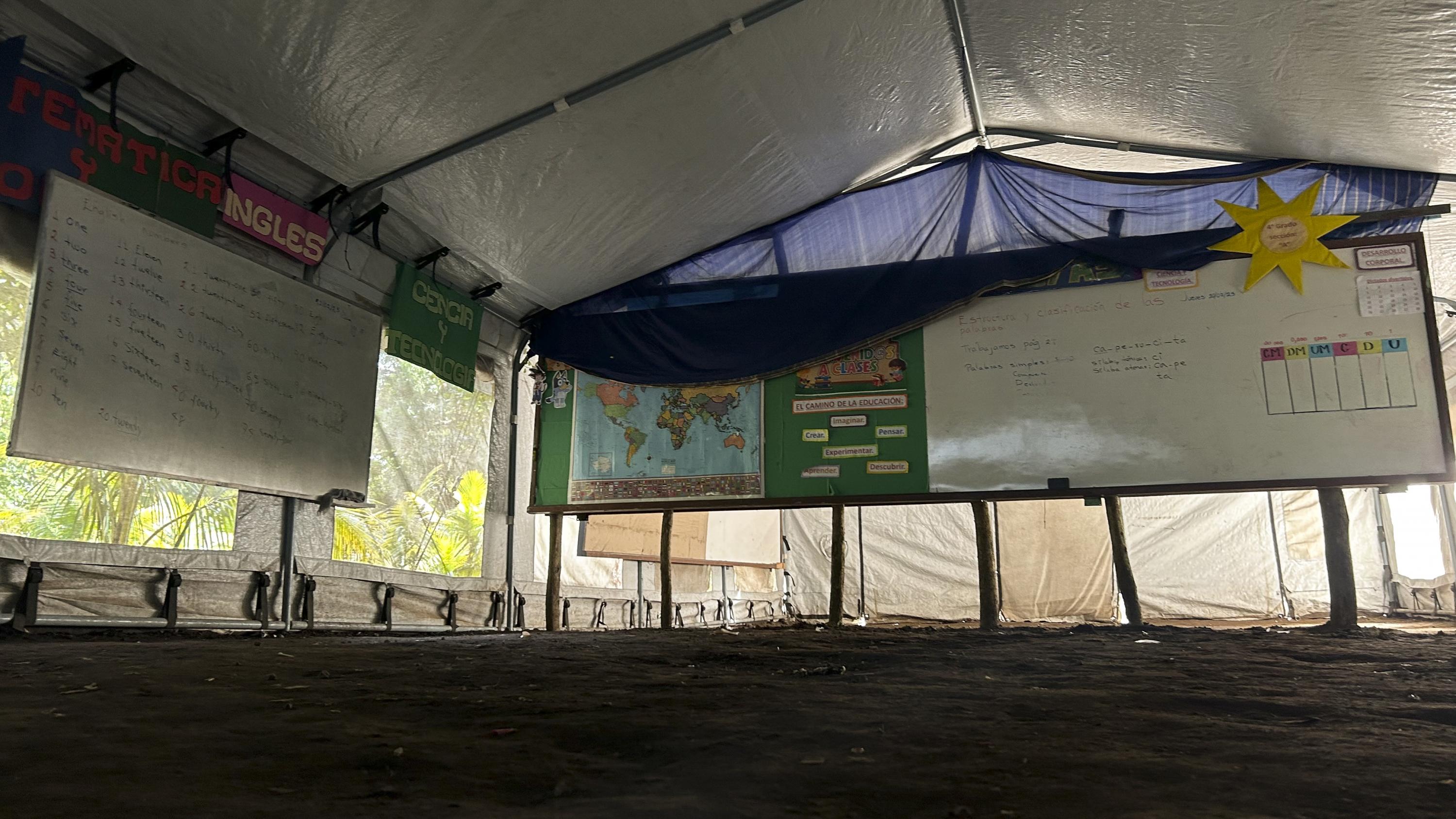 Interior del aula donde los alumnos reciben clases en el Centro Escolar Cantón Tapalshucut, en Izalco. Así lo hacen desde hace un año, sobre un piso de tierra y bajo una carpa con el logo de Unicef sotenida por tubos metálicos. Foto de El Faro: Víctor Peña. 