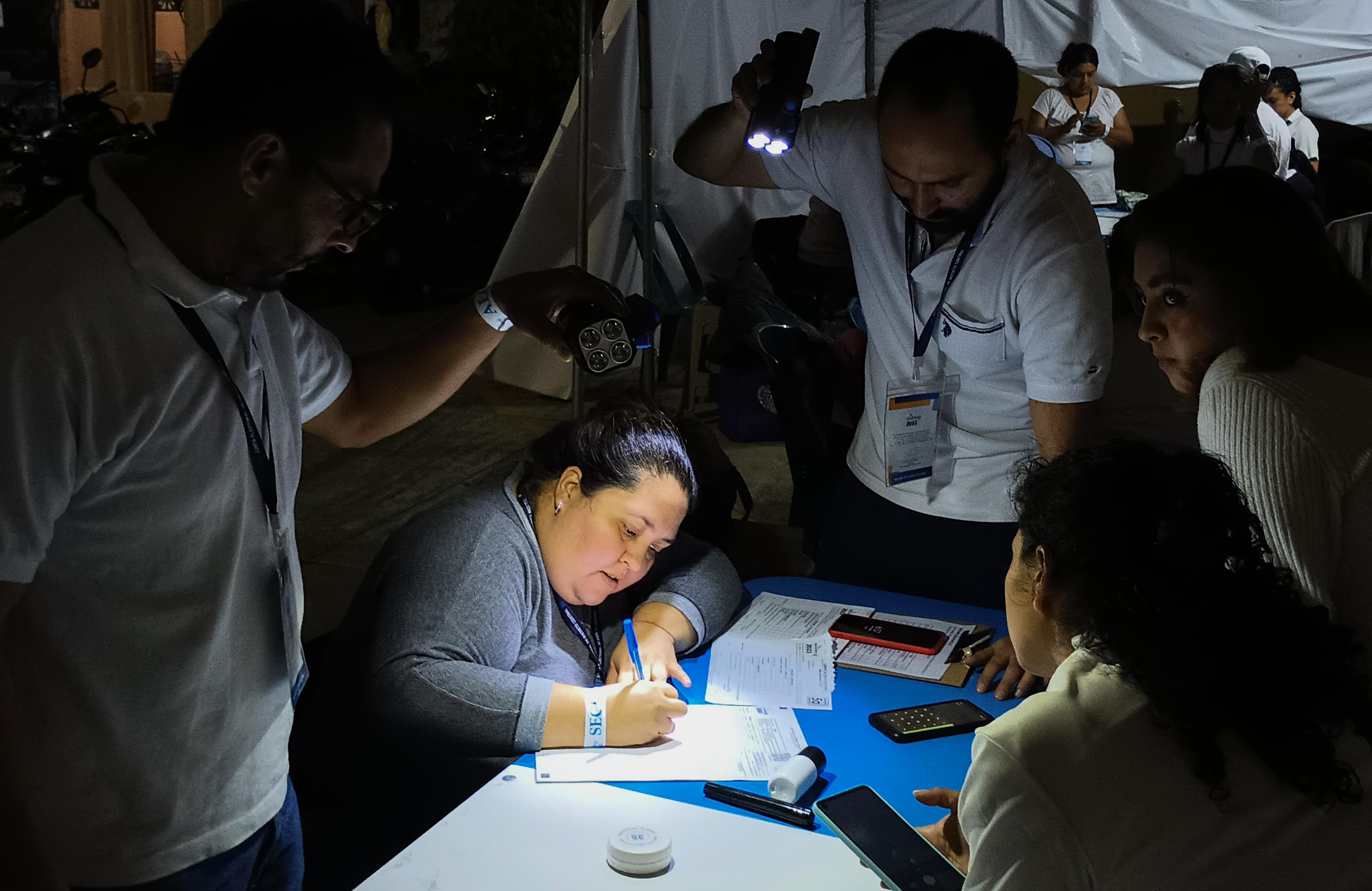 Leira Cruz Carlos, secretaria de la mesa 1897 en la Escuela Mixta Privada San Francisco de Asís, e la zona 7 de Ciudad de Guatemala, completa el acta de votación iluminada por una linterna. En esta Junta Receptora el Movimiento Semilla recibió 128 votos frente a 14 para la UNE. Foto de El Faro: José Luis Sanz.