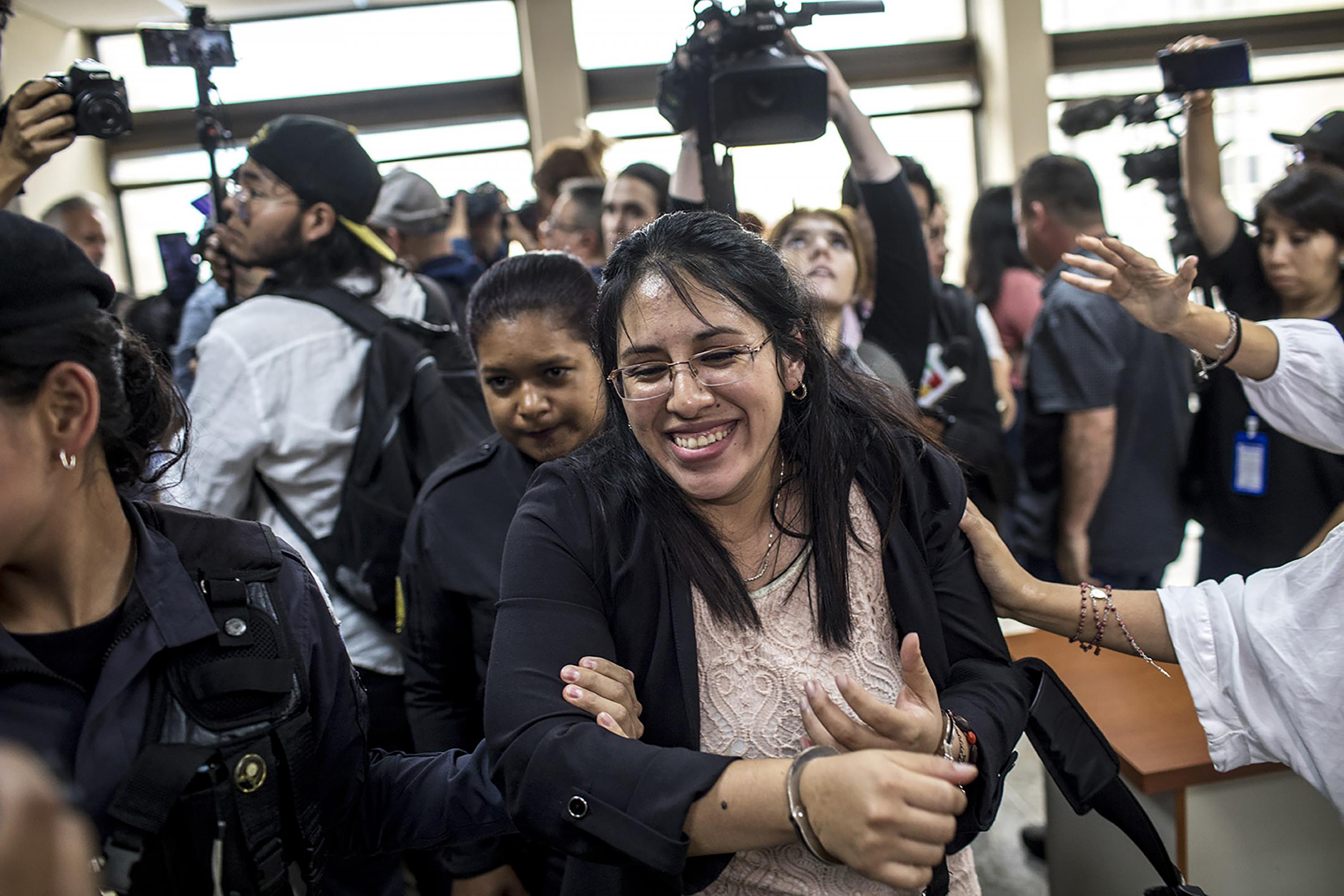 La ex auxiliar fiscal del MP, Samari Gómez, sale de la sala del Tribunal Octavo Penal sonriendo, mientras recibe las felicitaciones de dos amigas tras ser absuelta. Foto de El Faro: Simone Dalmasso/ Plaza Pública