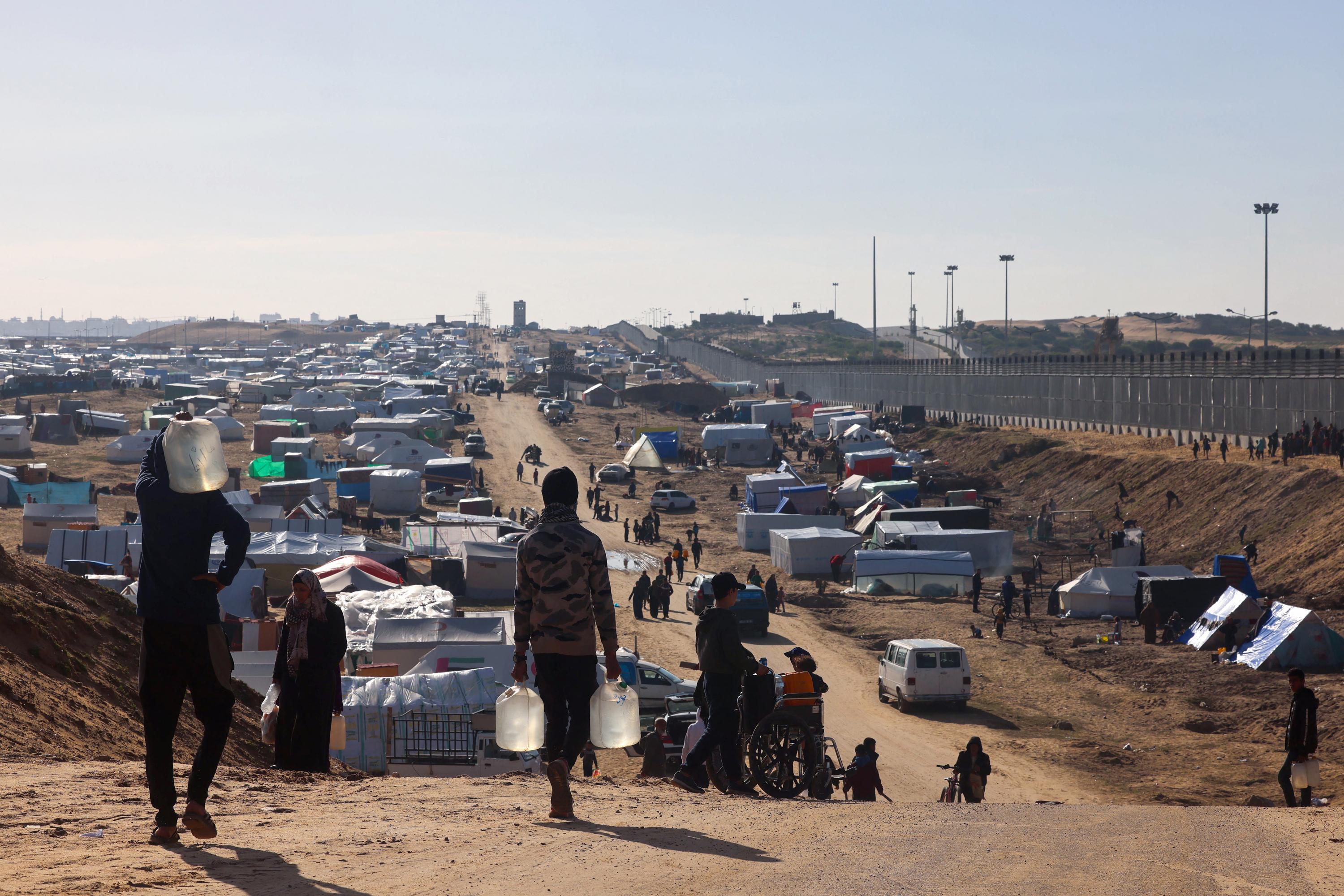 Un grupo de refugiados transporta agua en un campamento improvisado para palestinos desplazados en Rafah, cerca de la frontera con Egipto, al sur de la Franja de Gaza, el 24 de enero de 2024. Foto de El Faro: AFP.