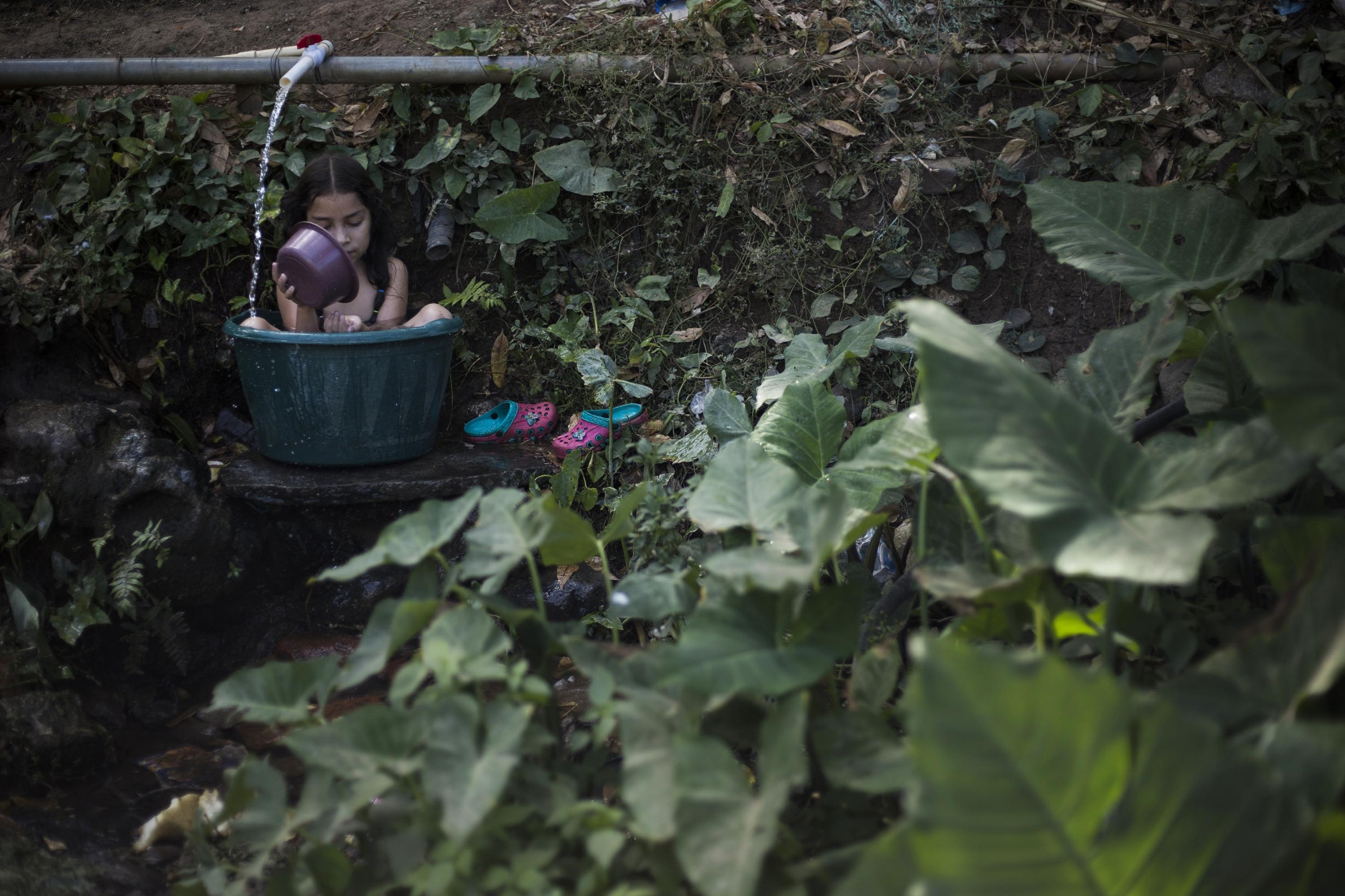 Adriana Monserrat arrives every afternoon to take hot water from the pipes near her home and take a bath in a large bucket. Other residents also travel to this point to fill up their water reserves.