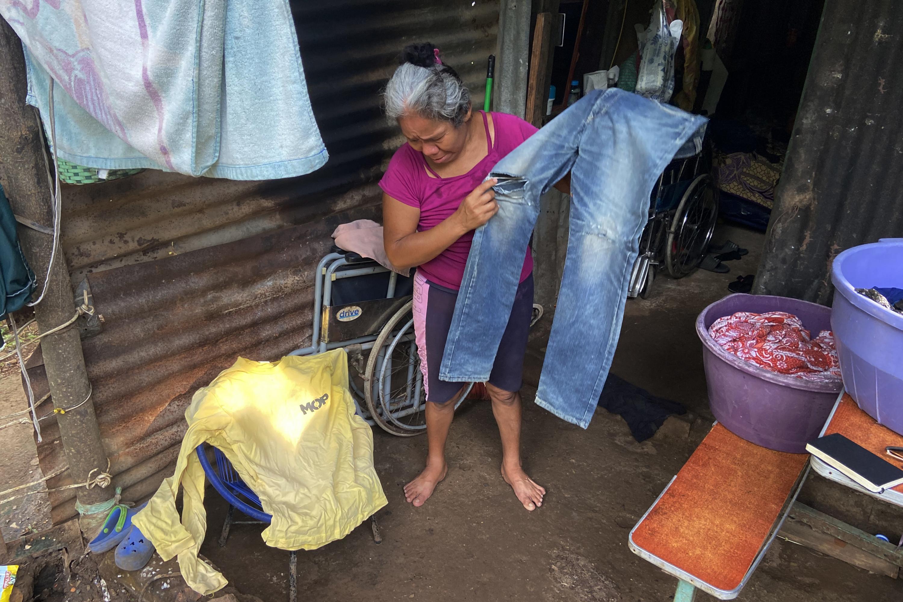 Ana, Juan Saúl’s mother, shows her son’s work clothes. Saúl was a bricklayer and worked on several projects overseen by the Ministry of Public Works, among them the road to Surf City. Photo Carlos Martínez