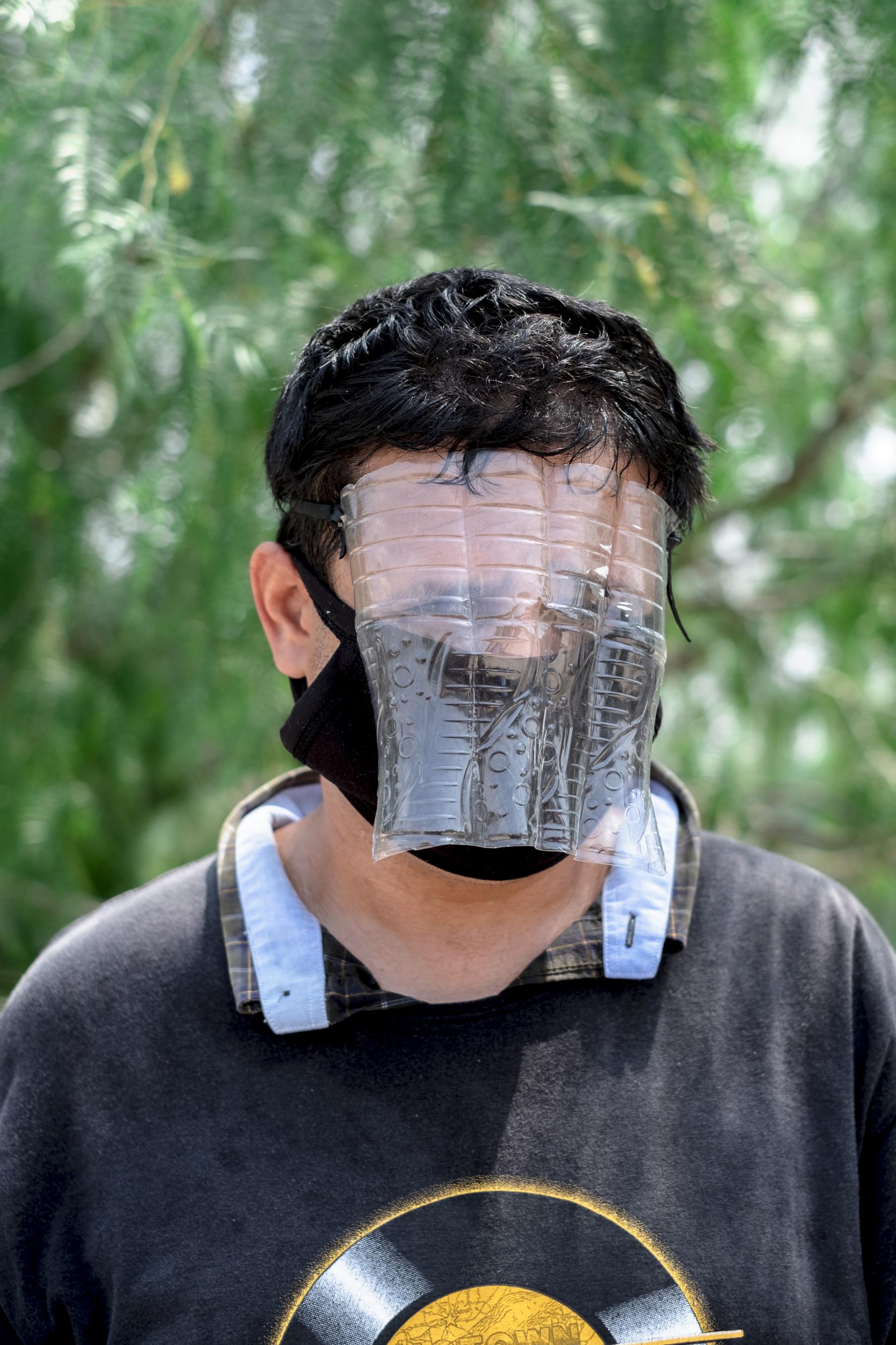 Jesús Hernández tiene 25 años y es originario de Matamoros. Es vendedor de dulces en diferentes puntos de la ciudad y llega a vender al campamento. Ha hecho una careta con una botella de plástico para protegerse del coronavirus.