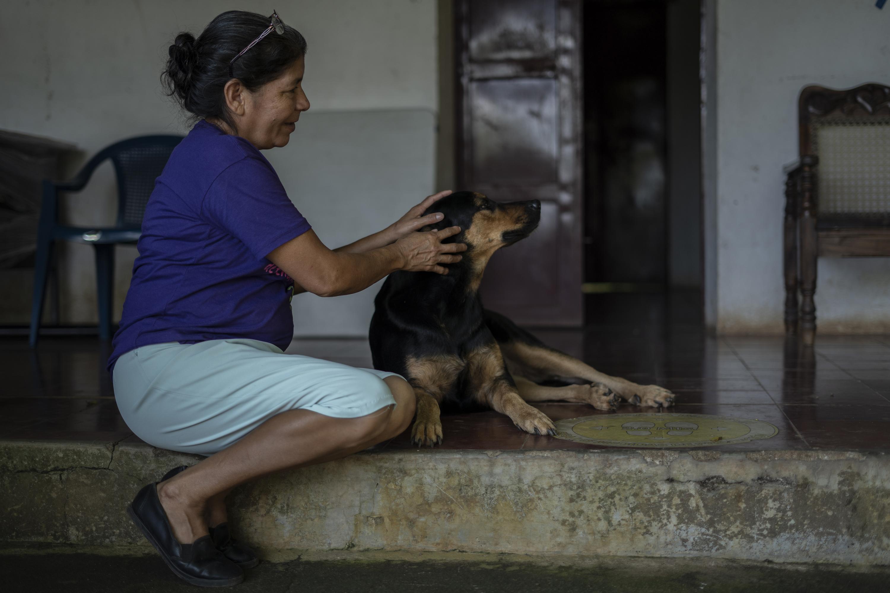 Vidalina Morales juega con Kira, su perra guardiana, en las oficinas de la Asociación de Desarrollo Económico y Social de Santa Marta (ADES), en el municipio de Guacotecti, departamento de Cabañas. Vidalina es lideresa histórica de su comunidad y una de las principales activistas contra la minería en El Salvador. Departamento de Cabañas, 14 de agosto de 2023. Foto de El Faro: Víctor Peña. 