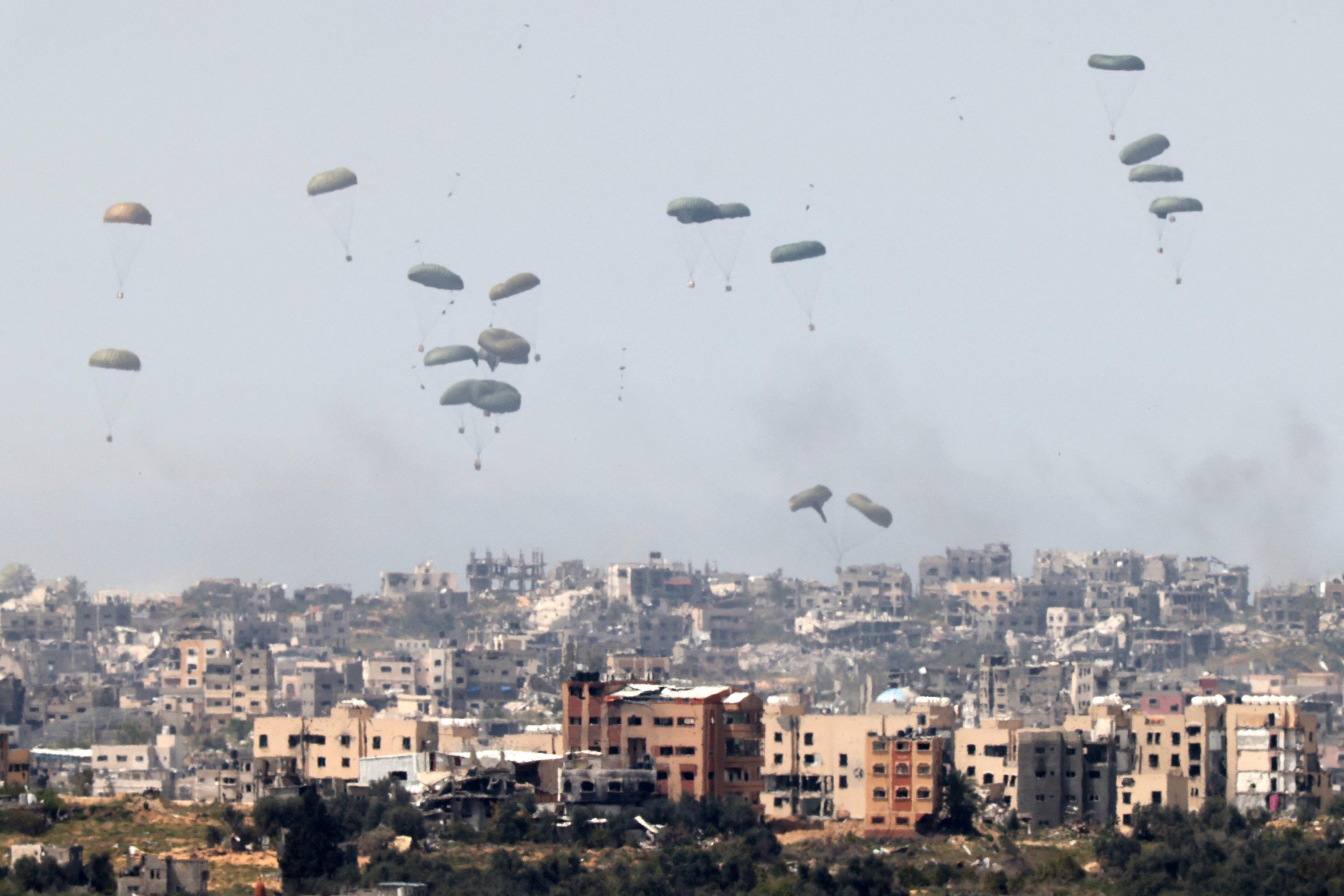 Un avión militar lanza paracaídas con ayuda humanitaria sobre el territorio palestino asediado el 27 de marzo de 2024, en la frontera sur de Israel y la Franja de Gaza. Foto de El Faro: Jack Guez/ AFP.