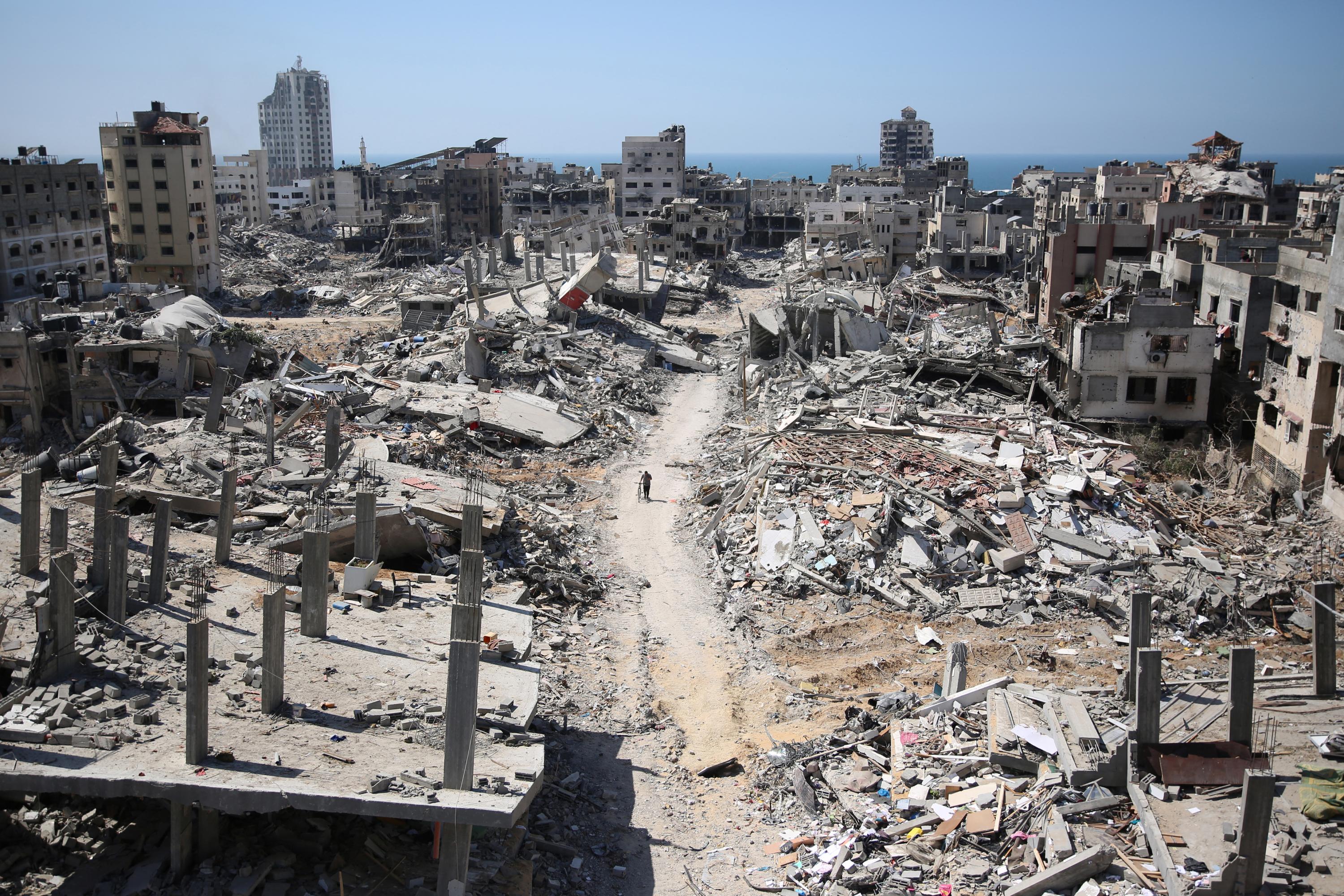 A man pushes a bycicle along as he walks amid building rubble in the devastated area around Gaza