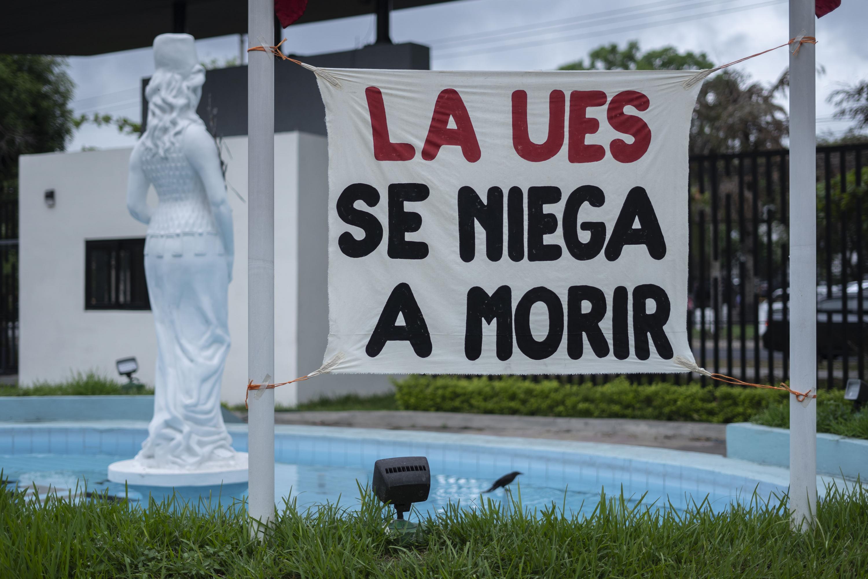 La frase célebre del rector asesinado en 1980, Félix Ulloa padre, se lee sobre la entrada prinicipal de la Universidad de El Salvador. Esa consigna quedó colocada en la plaza Minerva desde las protestas del primero de mayo de 2024. Actualmente, el hijo del rector asesinado es vicepresidente de Bukele. Foto de El Faro: Víctor Peña. 