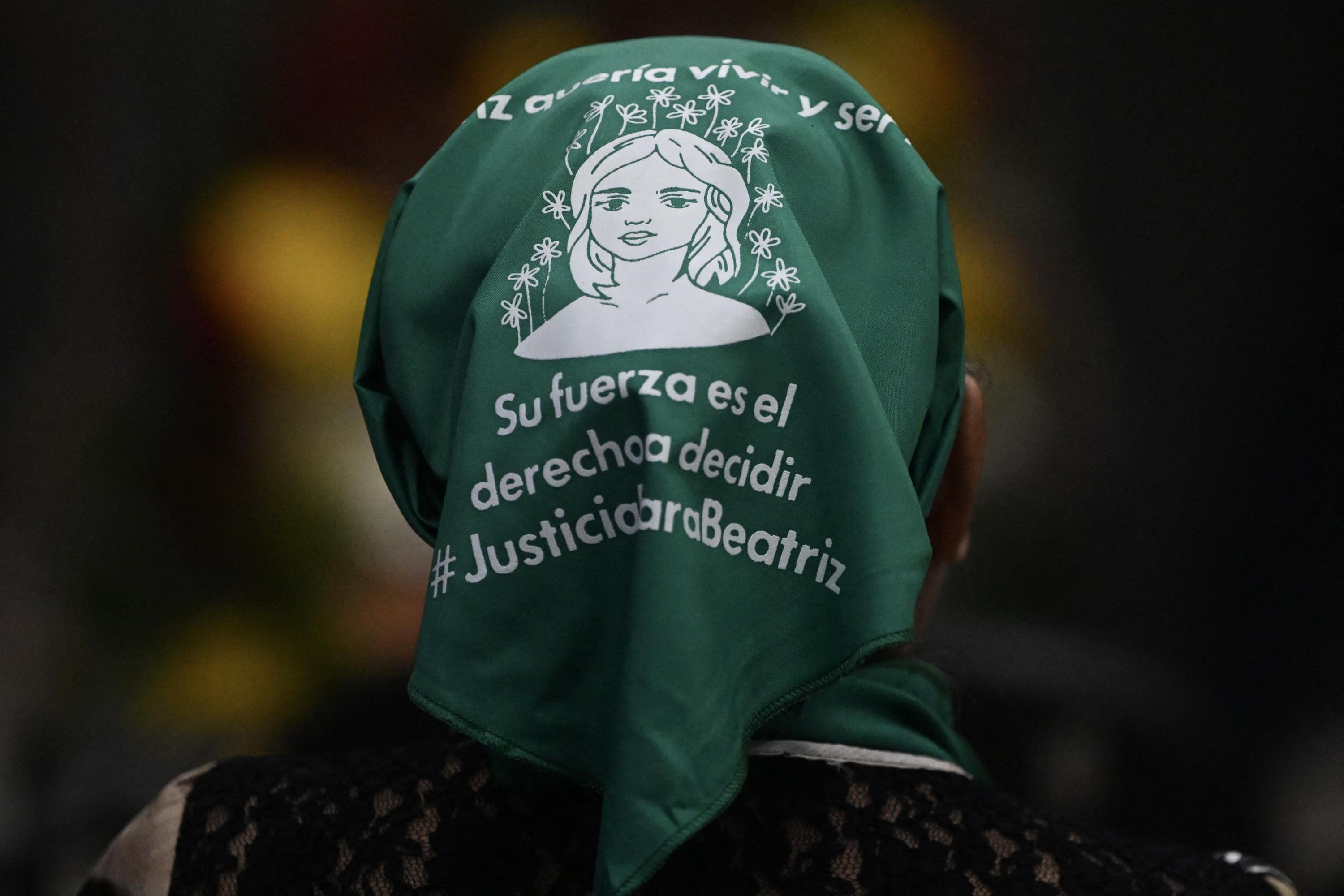 A woman wears a green handkerchief in support of the case of Beatriz and others v. El Salvador , in San Salvador, on March 22, 2023, during a live broadcast from the Inter-American Court of Human Rights in Costa Rica. Photo Marvin Recinos/AFP