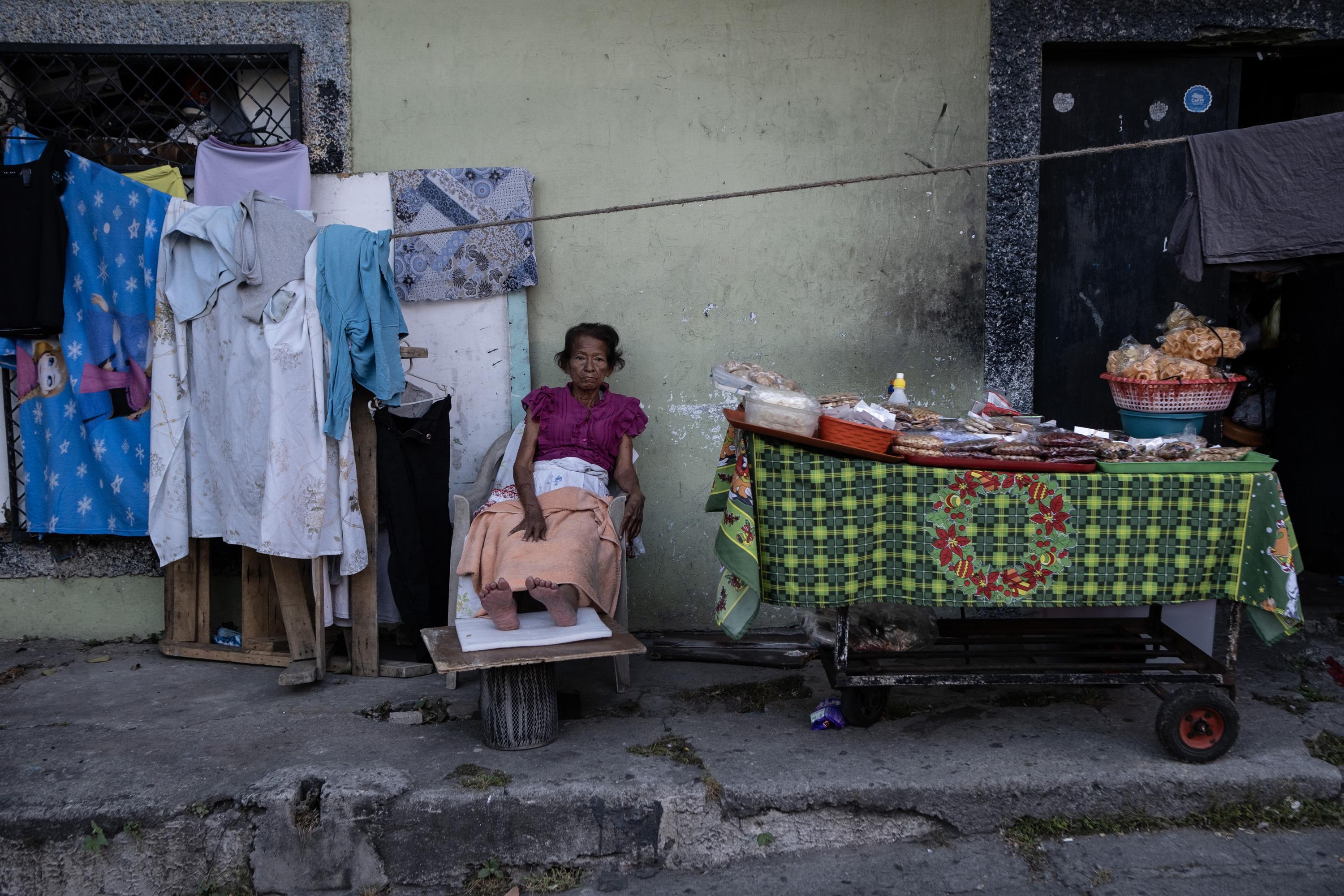 Elva Martínez,  de 65 años, pasa sus días postrada en una silla frente al lugar donde renta un cuarto por $70 mensuales. Es diabética y hace un mes sufrió un desmayo que le causó un grave golpe en la cadera y el hombro derecho. Tiene sus pies inflamados, eso le impide salir a buscar latas para luego venderlas en alguna chatarrera. Sobrevive de una venta de dulces, con lo que apenas logra cubrir el pago de su habitación. Hace dos meses el encargado del mesón que habita le anunció que le aumentaría $15 de renta. Elva no aceptó, es dinero que se le hace imposible pagar y se ha quedado a la espera de que le mantengan el precio o la desalojen. Foto de El Faro: Carlos Barrera