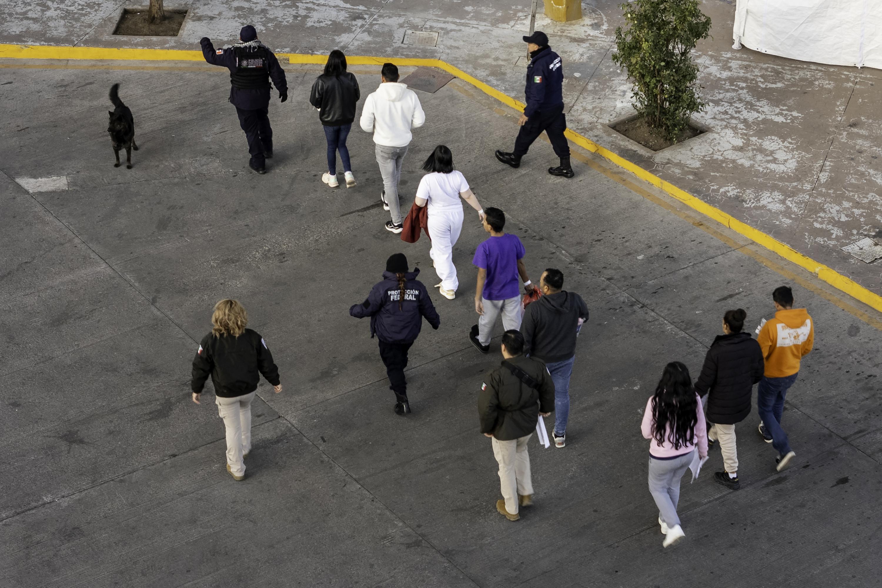 Funcionarios de inmigración y policías mexicanos escoltan a un grupo de migrantes deportados que fueron enviados de regreso a México, el 22 de enero de 2025, visto desde el punto fronterizo en Nogales, Arizona. El presidente de Estados Unidos, Donald Trump, firmó órdenes ejecutivas en su primer día en el cargo declarando el estado de emergencia en la frontera sur de Estados Unidos. Foto de El Faro: John Moore/ AFP/ Getty Images.