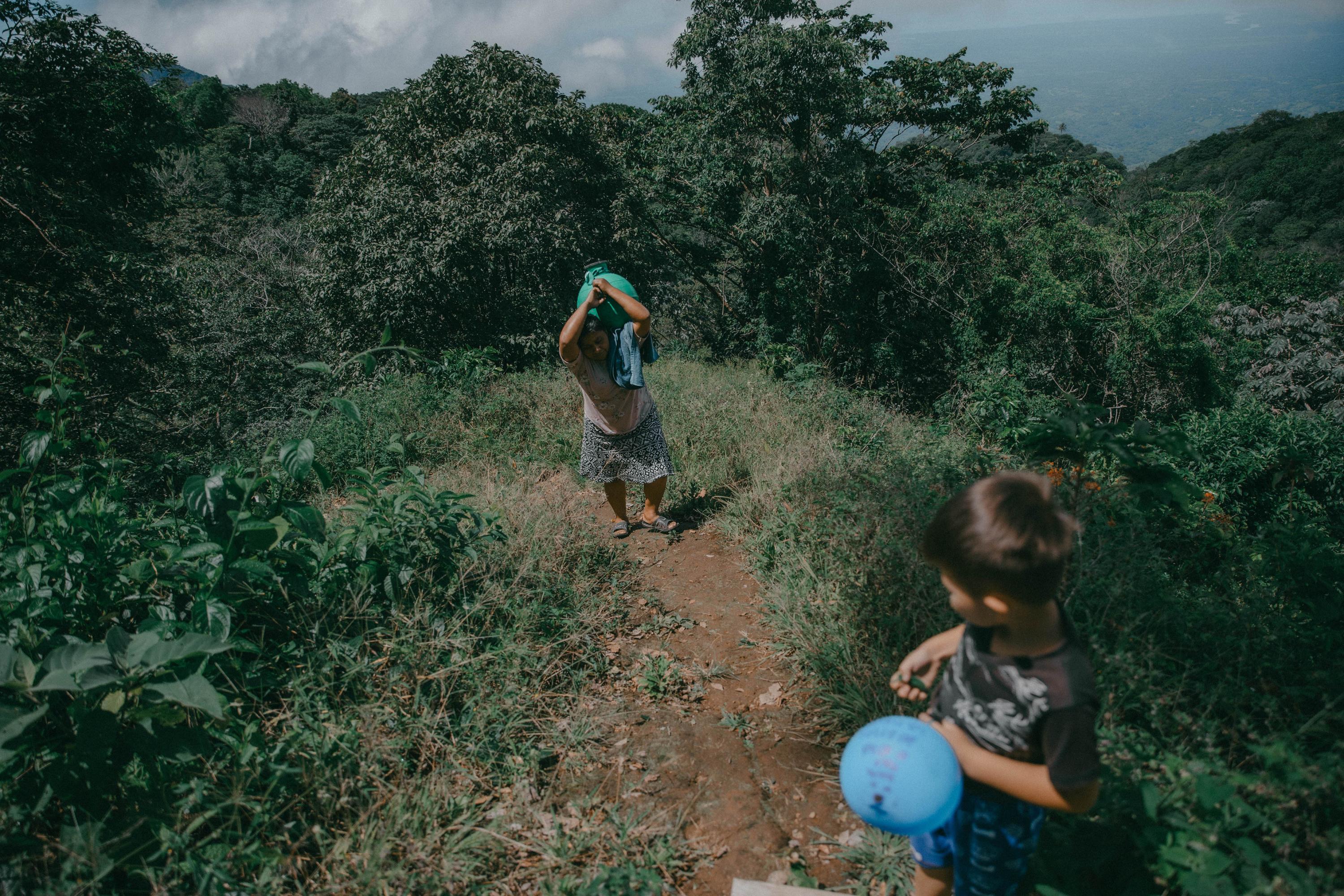 Para conseguir agua, María Aguilar, de 45 años, camina todos los días entre barrancos y pendientes al lado de su sobrino de cinco años. Ella es la encargada de las labores domésticas de su casa, lo que incluye el abastecimiento de agua para consumo y limpieza. Vive junto al resto de su familia en la comunidad San Lorenzo, en la periferia del casco urbano de Berlín. 