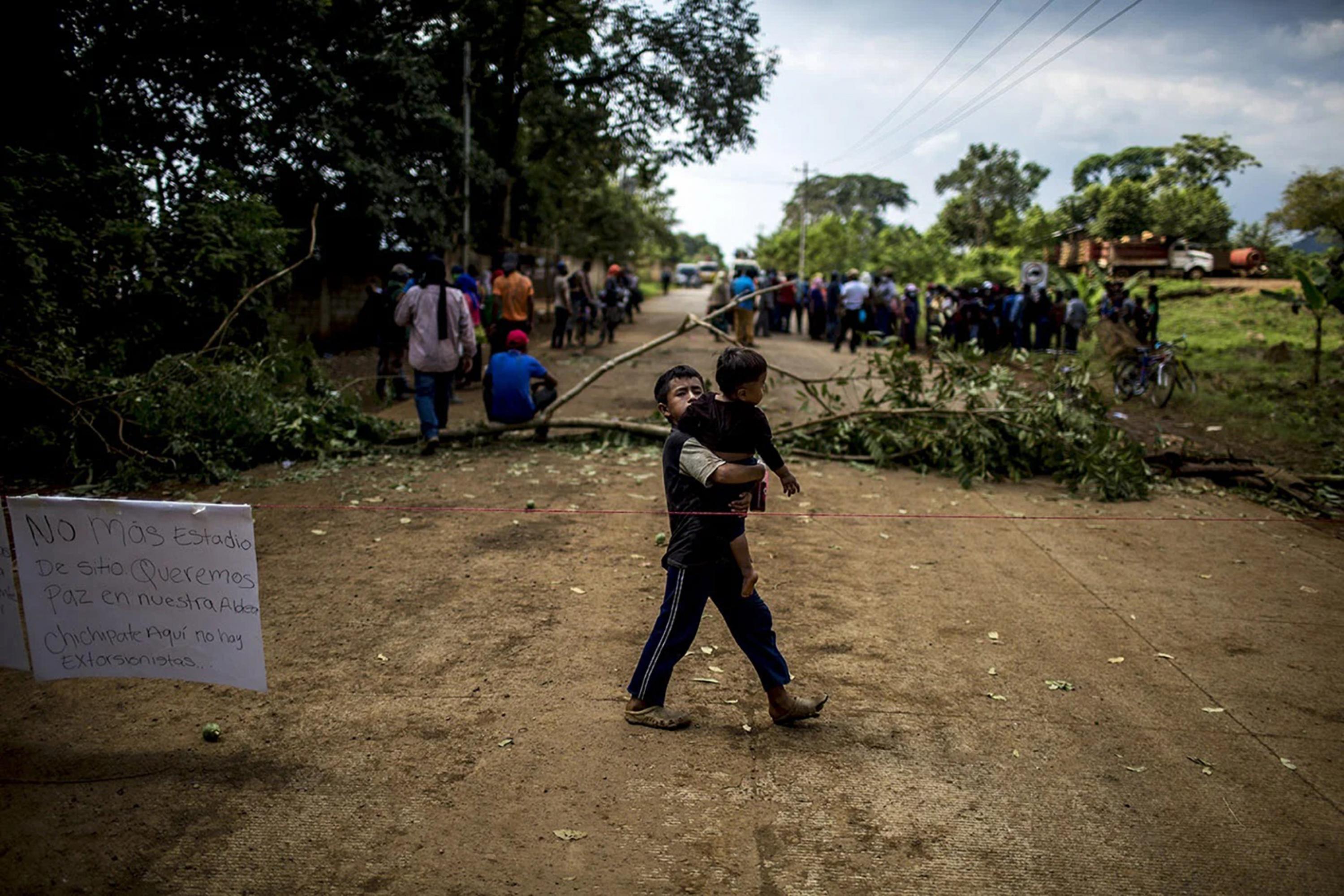 A child carries his brother in a blockade of the highway to Panzós, in Chichipate, Izabal, on Oct. 30, 2021, one week after the Giammattei administration enacted a state of siege there. Photo Simone Dalmasso/Plaza Pública