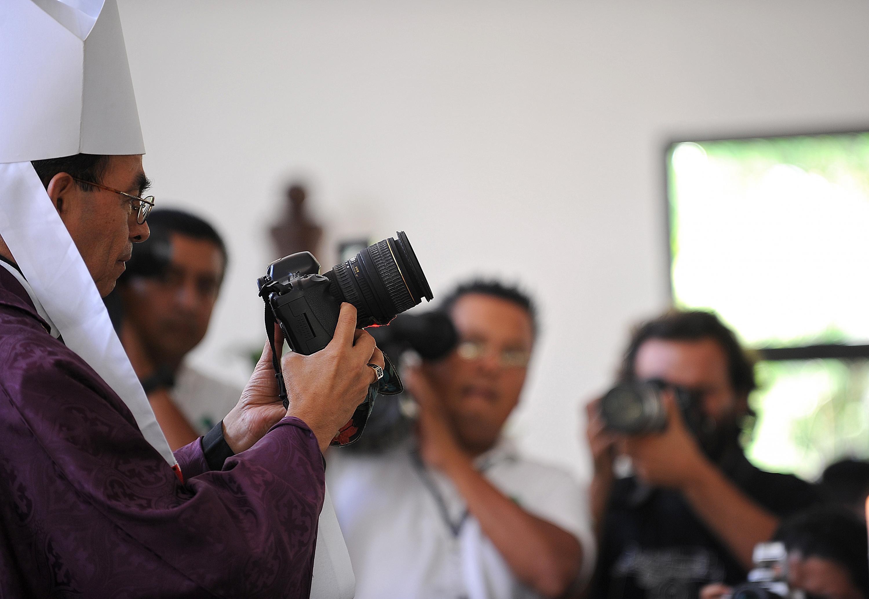 El obispo Gregorio Rosa Chávez sostiene la cámara de Christian Poveda durante una misa del funeral  del fotoperiodista. La foto es del 9 de septiembre de 2009. Foto: Yuri Cortez / AFP 