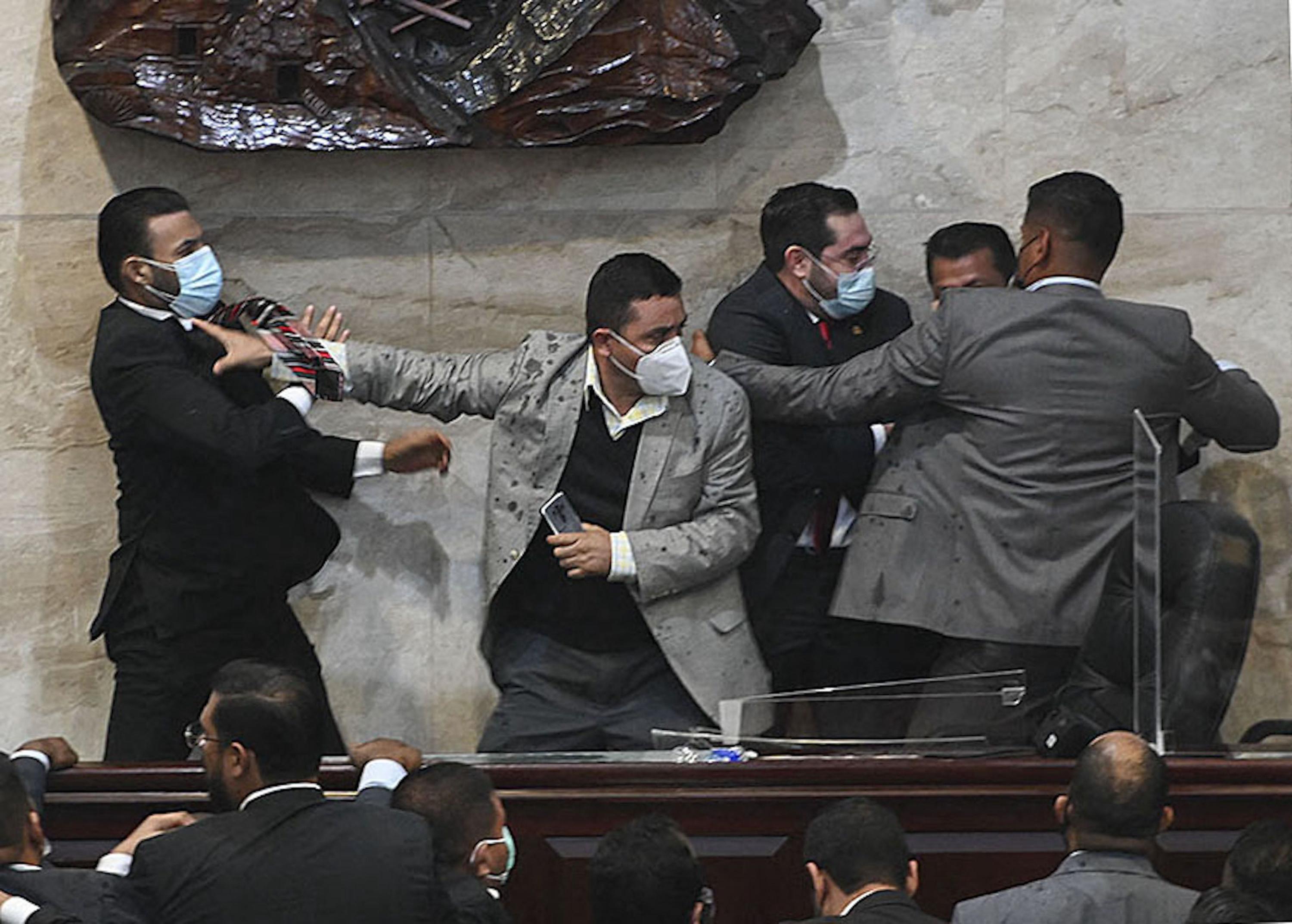 El diputado para el partido Libre Rassel Tome (izquierda) trata de asaltar al diputado Jorge Cálix (segundo a la derecha), que había roto con el partido oficialista, tras su elección como presidente del consejo provisional de directores del Congreso Nacional el 21 de enero de 2022, una semana antes de la toma de posesión de la presidenta Xiomara Castro. Foto de El Faro: Orlando Sierra/AFP