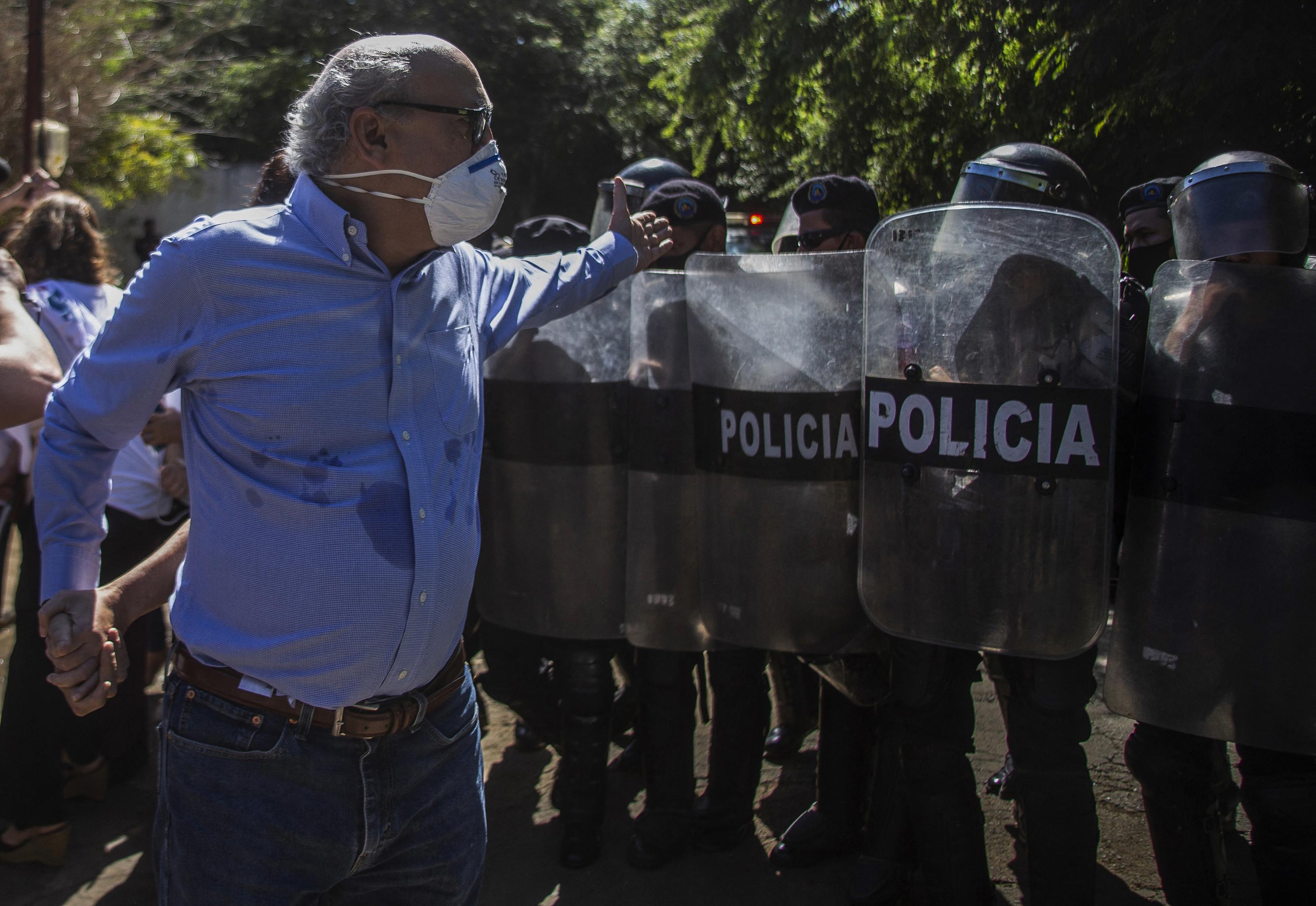 Nicaraguan journalist Carlos Fernando Chamorro, director of El Confidencial and of the televised news program Esta Semana, is pushed back by riot police on December 14, 2020 in front of the El Confidencial offices in Managua, seized two years earlier by the regime of President Daniel Ortega. Photo AFP
