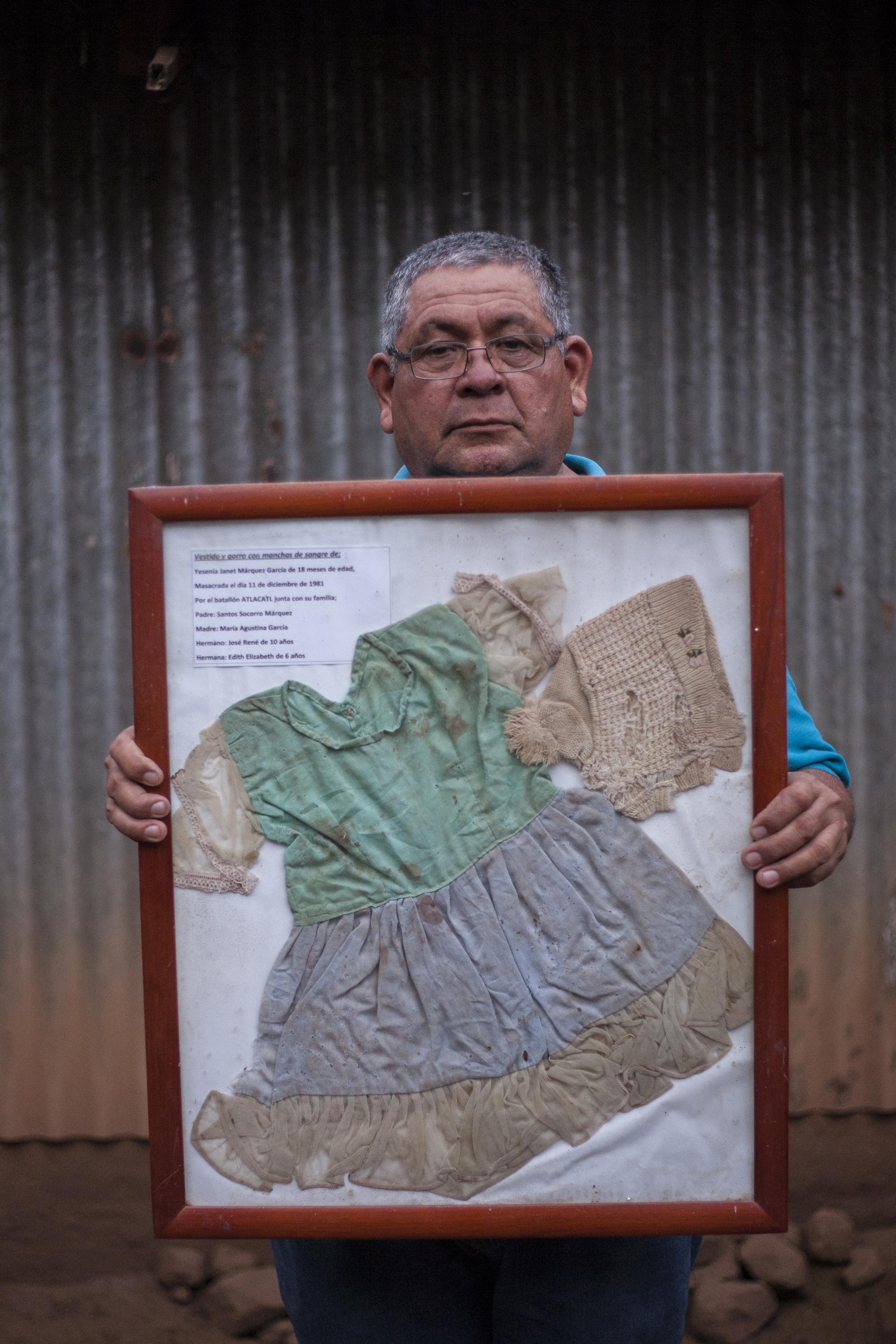 Orlando Marquez muestra el vestido de su hermana. Yesenia Janet Márquez García, quien fue asesinada a los 18 meses de vida durante la masacre de El Mozote, perpetrada el 11 de diciembre de 1981. Foto de El Faro: Víctor Peña. 