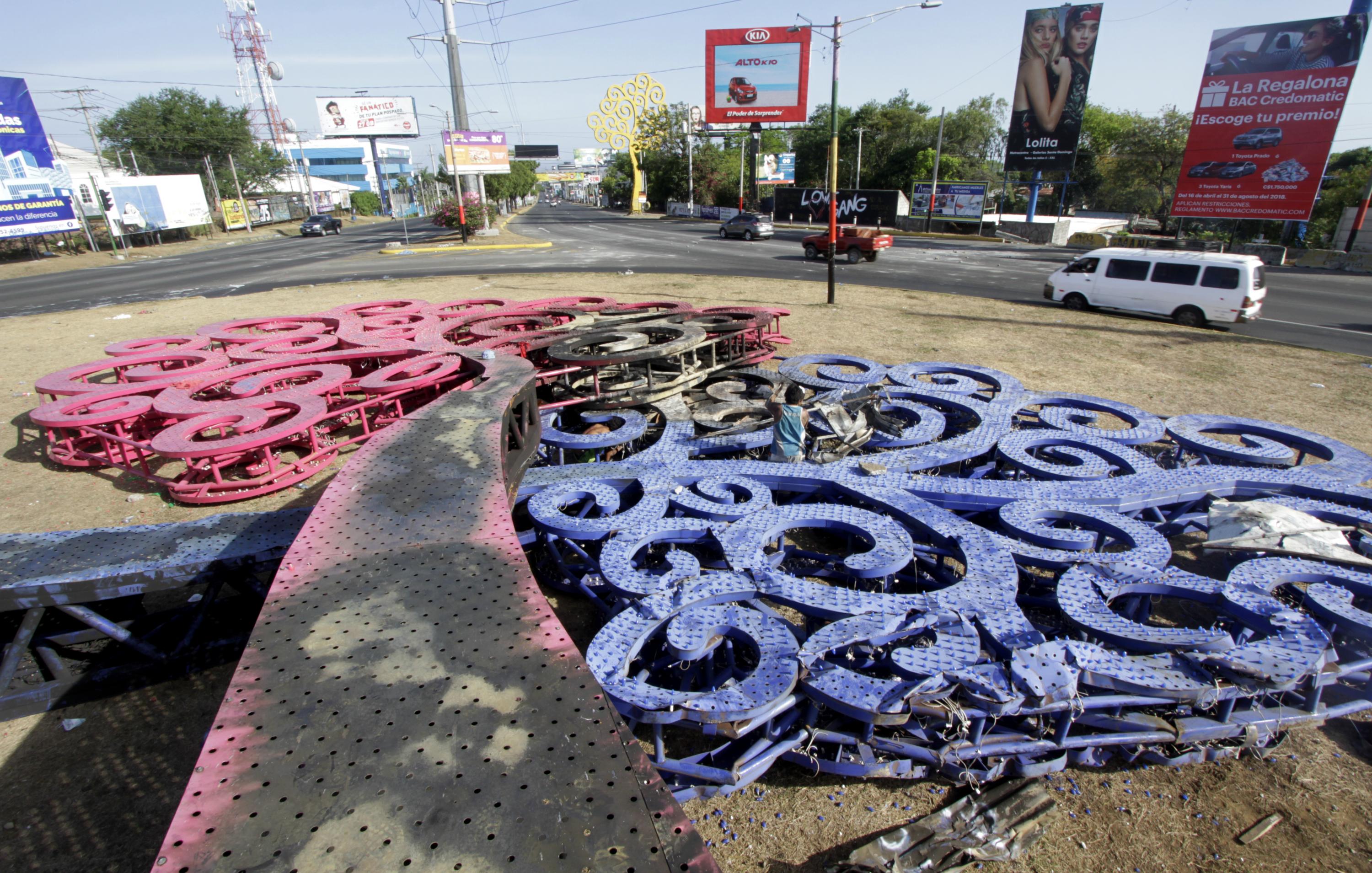 Un grupo de hombres cortó piezas metálicas para vender en el mercado los restos del árbol de acero, monumentos simbólicos del gobierno del Frente Sandinista nicaragüense. Los monumentos fueron incendiados y derribados durante una protesta contra las reformas del gobierno en el Instituto de Seguridad Social (INSS), en Managua el 22 de abril de 2018 AFP PHOTO / INTI OCON