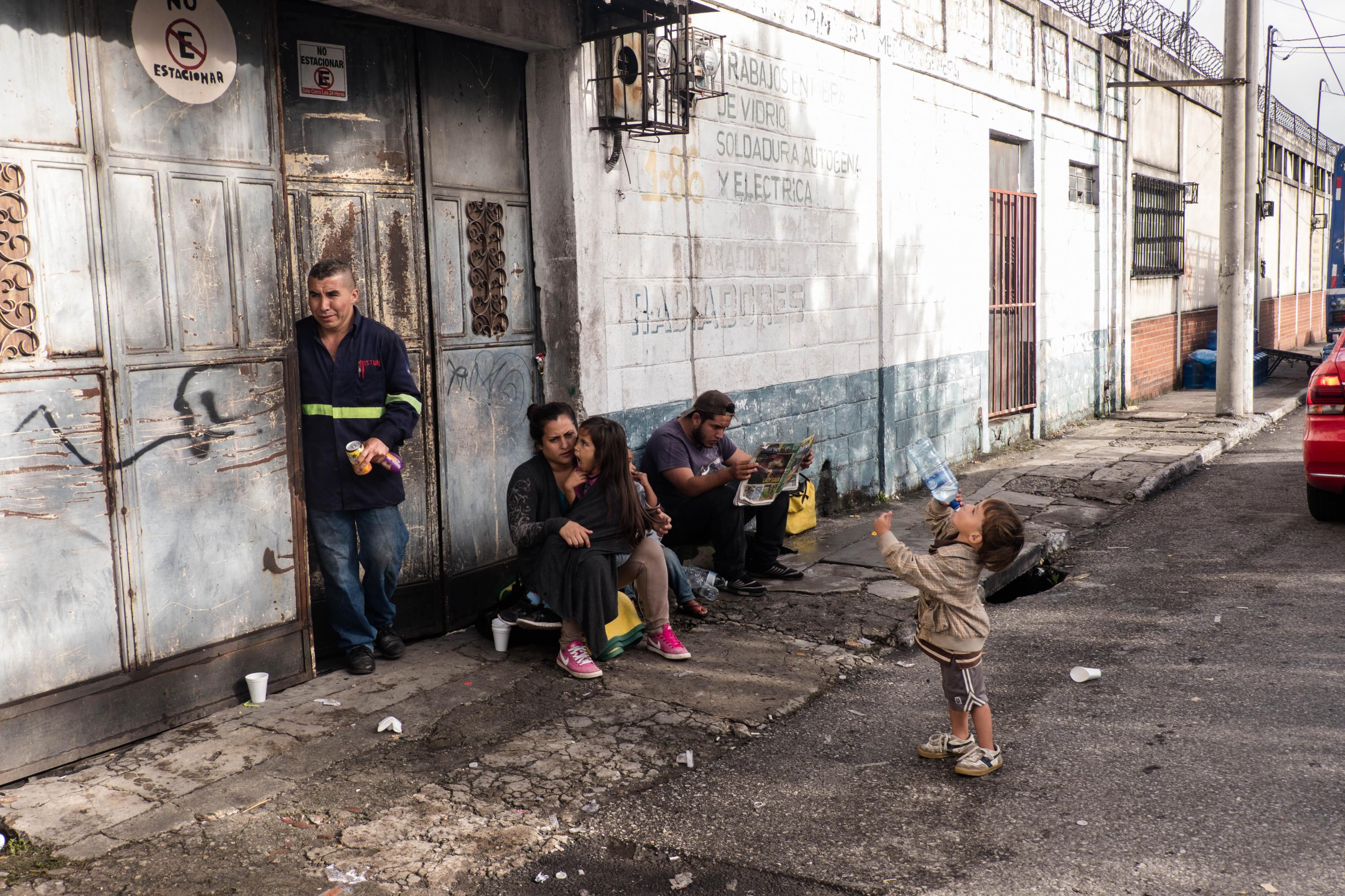 Una familia de hondureños, procedentes de San Pedro Sula, descansa un momento afuera de un taller mecánico en los alrededores de La Casa de Migrante, en Ciudad de Guatemala, el 18 de octubre de 2018. Foto: Fred Ramos