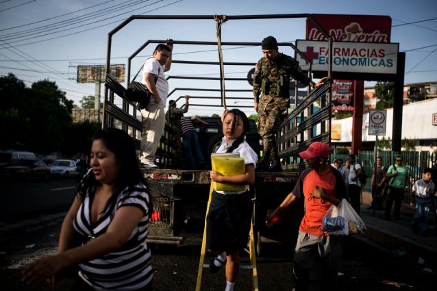 En la colonia Zacamil, en Mejicanos durante el cuarto y último día del paro de transporte, una estudiante se baja de uno de los camiones militares brindados por el estado como alternativa durante para que los ciudadanos puedan llegar a sus destinos. Fotografía de la galería 