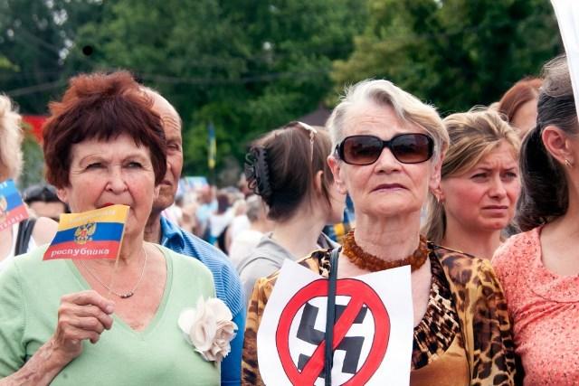 Mujeres portan rótulos con svasticas durante una protesta ante elecciones organizada por simpatizantes prorrusos en el noreste de Ucrania, el domingo 25 de mayo. El empresario de chocolate Petro Poroshenko clamó victoria. Foto de AFP / Sergey Bobok. 