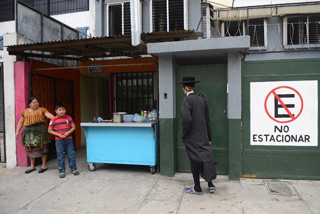 Una mujer y su hijo observan a un miembro de la secta ultra ortodoxa judía frente al edificio al cual se han visto obligados a trasladarse después de ser expulsados de San Juan La Laguna por la comunidad indígena local. Foto AFP/Johan Ordoñez