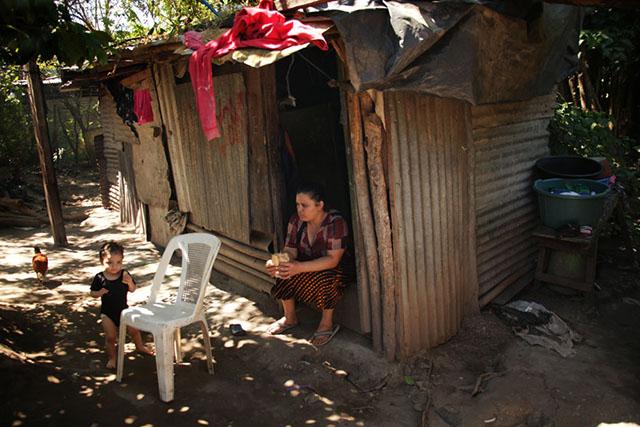 Vilma Rivas cuida a la menor de sus 5 hijos que viven en esta casa de láminas en la comunidad El Espino. De los 126 asociados de la Cooperativa El Espino que había para 2008, 96 eran hombres y el resto, mujeres. Entre las tareas que deben realizar es el cuidado de los familiares. Las circunstancias no siempre son las más fáciles, sobre todo en una comunidad sin servicios como el agua potable o la electricidad. Foto archivo El Faro/Mauro Arias