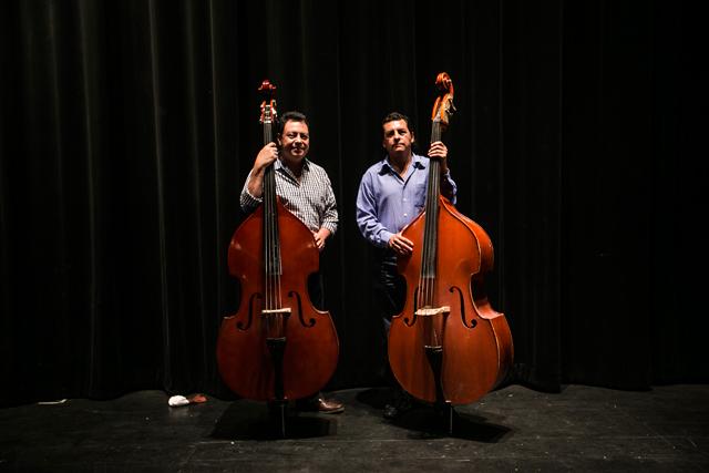 Guillermo segundo y José Alberto Caminos Dimas aprendieron a tocar el contrabajo con su padre. El único instrumento con el que cuenta cada uno, sin embargo, es un contrabajo eléctrico, que les sirve para trabajar en bandas y orquestas de música popular. Foto: Fred Ramos.