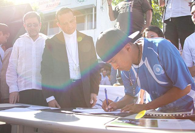 Un pandillero firma un acuerdo de paz entre pandillas en Ilopango bajo la mirada de Fabio Colindres y David Munguía. 22 de enero 2013. Foto Mauro Arias