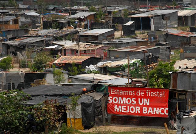 Los restos de un rótulo publicitario de un banco era utilizado en la comunidad Las Victorias de Soyapango como material de construcción para una pared de una champa de láminas. Foto Archivo/Mauro Arias