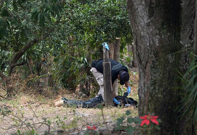 Un agente del equipo de Inspecciones Oculares de la Policía Nacional Civil revisa el cadáver de José Antonio Gómez, alias Güereja, en la mañana del 26 de marzo de 2015. La escena ocurre en la finca San Blas, del municipio de San José Villanueva, departamento de La Libertad. El Faro reveló en julio que la PNC había perpetrado ejecuciones sumarias ahí. Foto: Archivo de El Faro.