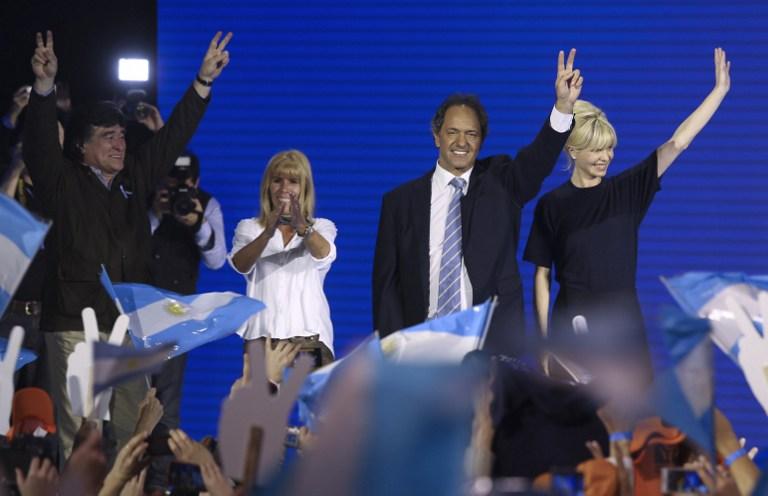 El gobernador de la provincia de Buenos Aires, Daniel Scioli (de corbata, al centro), saluda a sus seguidores, tras proclamarse ganador de las elecciones primarias por la presidencia argentina, realizadas este domingo. Las elecciones seran en octubre y Scioli representa la opcion unica del oficialismo. Foto AFP/ TNA / DAMIAN DOPACIO 