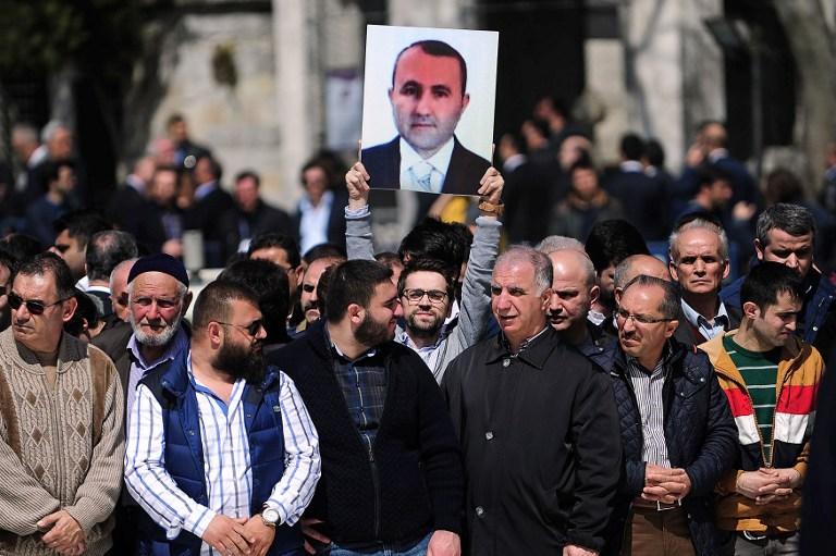 Un hombre sostiene un retrato de Mehmet Selim Kiraz, fiscal asesinado el 1 de abril. Las autoridades turcas detuvieron a másde 30 presuntos miembros de un grupo armado que se denomina Partido Revolucionario de Liberación Popular - Frente (DHKP/C). La muerte del fiscal ha conmocionado al país. AFP PHOTO / OZAN Kose