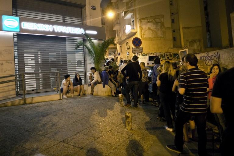 Ciudadanos griegos hacen fila frente a un cajero automático para retirar efectivo del Banco Nacional de Grecia, al cerntro de Atenas, el domingo 28 de junio. El gobierno griego decretó severas restricciones bancarias para evitar un posible colapso financiero, a medida que los ciudadanos ansiosos vaciaron los cajeros automáticos, en medio de miedos sobre el cierre de los bancos, efectivo desde este lunes 29 de julio. Foto AFP.