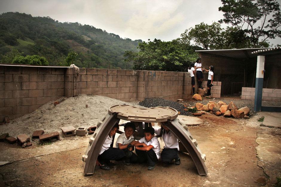 Unos niños juegan en el patio de la escuela durante el recreo. Aprovechan los restos de una tarima para juegos donada por una ONG. A poco tiempo de la donación, el mueble está destruido por no estar diseñaro para el uso que le dan cientos de alumnos del centro escolar.