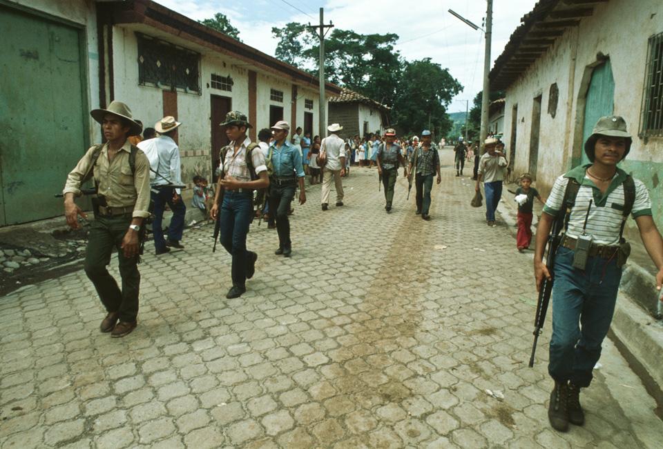 1983. Guerrilleros caminan por un pueblo del norte de Morazán