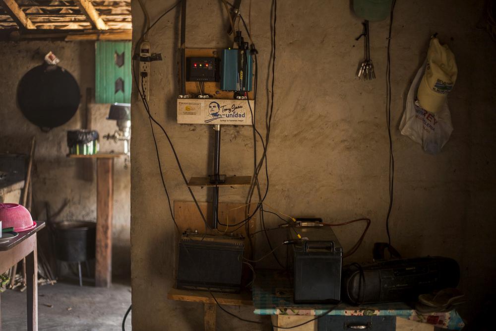 De las 39 casas del caserío El Volcán, sólo tres tienen habilitado un sistema que les permite almacenar la energía recogida de paneles solares. Eso les permite ver televisión, cargar teléfonos celulares y, en el caso de una de las viviendas, usar bombillos, lo que la hace única en medio de la oscuridad nocturna.