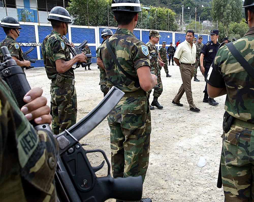 El expresidente Francisco Flores saluda a las tropas que apoyaban en labores de seguridad pública en el municipio de San Marcos. Lo acompaña el exministro de la Defensa, Juan Antonio Martínez, y el exdirector de la Policía, Ricardo Meneses. En este evento se lanzó la segunda fase del plan Mano Dura, el 30 de enero de 2004. Flores elevó las pandillas al estatus de enemigo público número uno. Foto: AFP / Yuri Cortez.